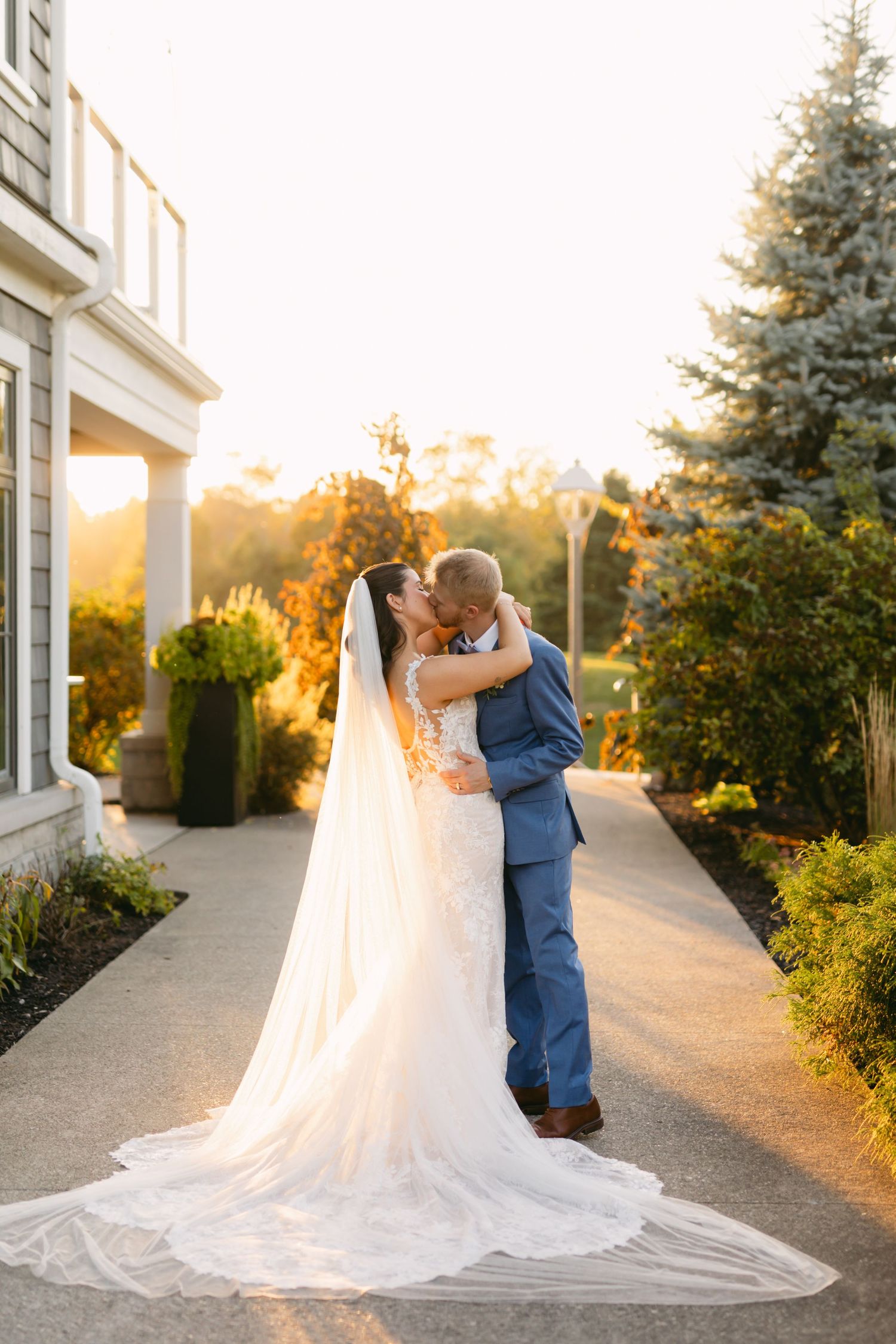 Wedding couple sharing romantic moment on pathway during golden hour sunset.
