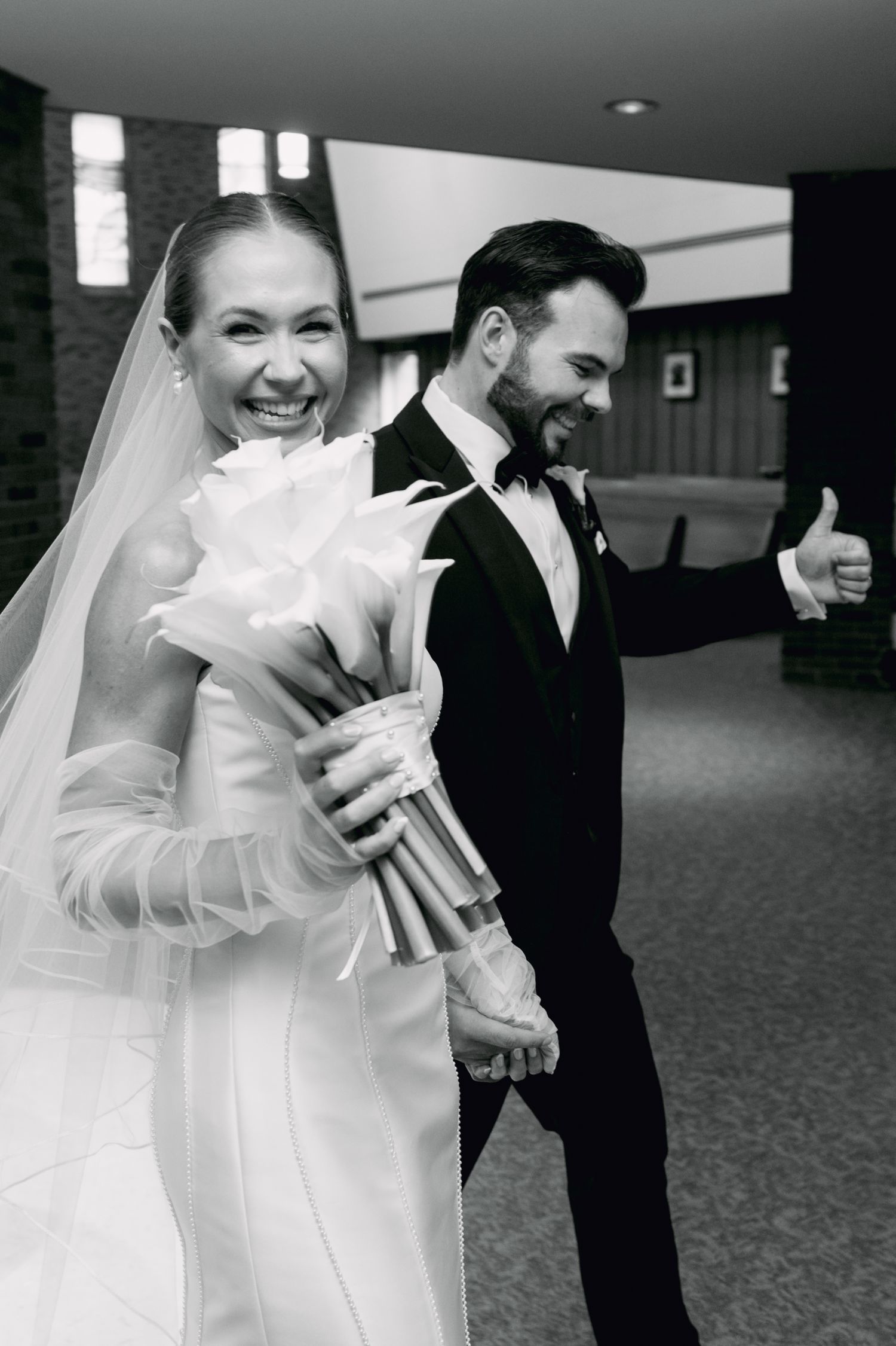 Joyful bride and groom laughing together in church after wedding ceremony in black and white.