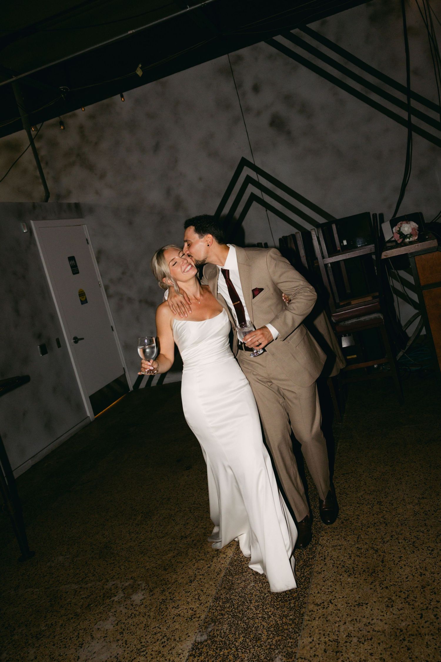 Wedding couple sharing a romantic dance moment in a dimly lit venue.
