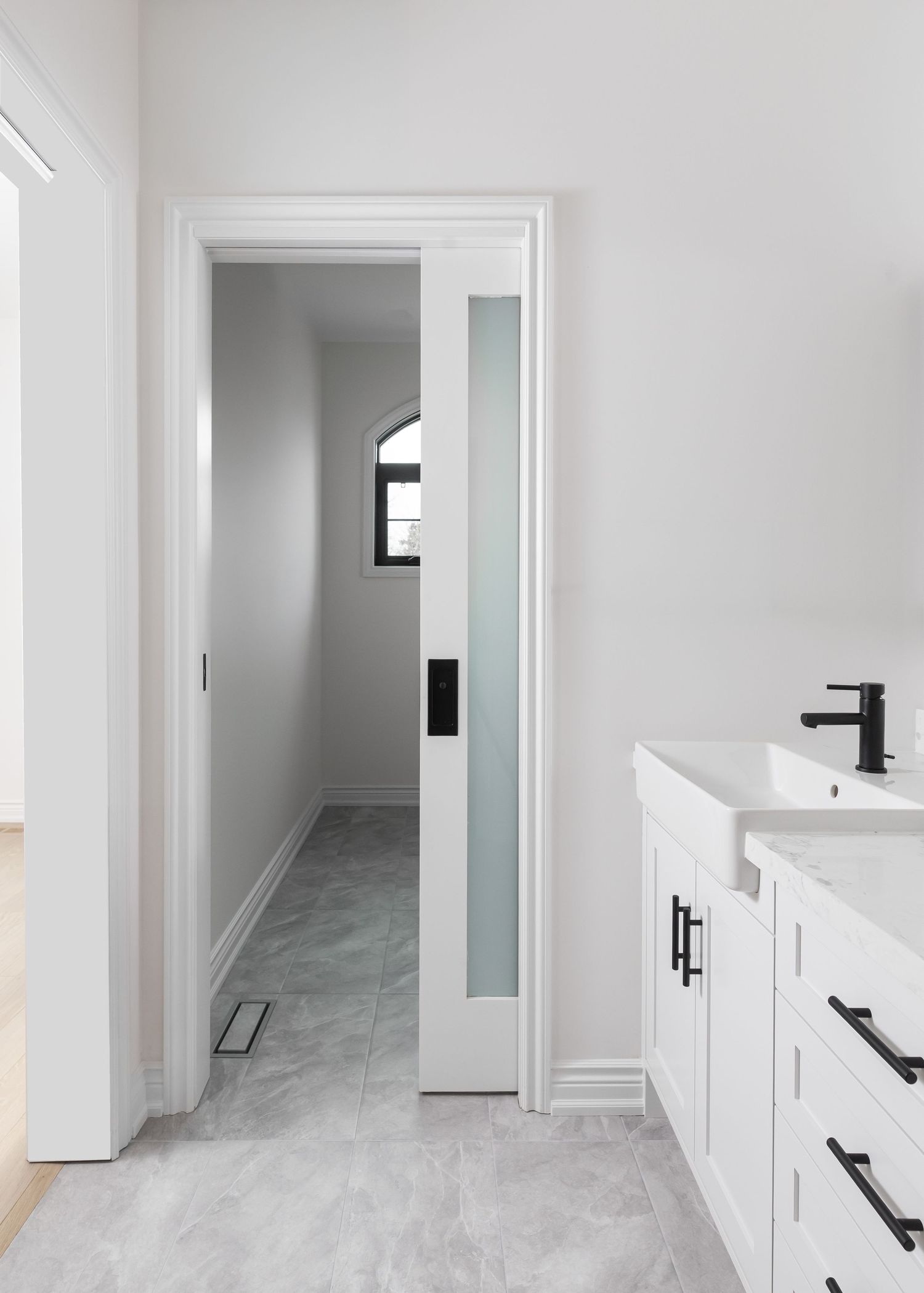 Clean white bathroom hallway with sliding door and modern cabinet storage.