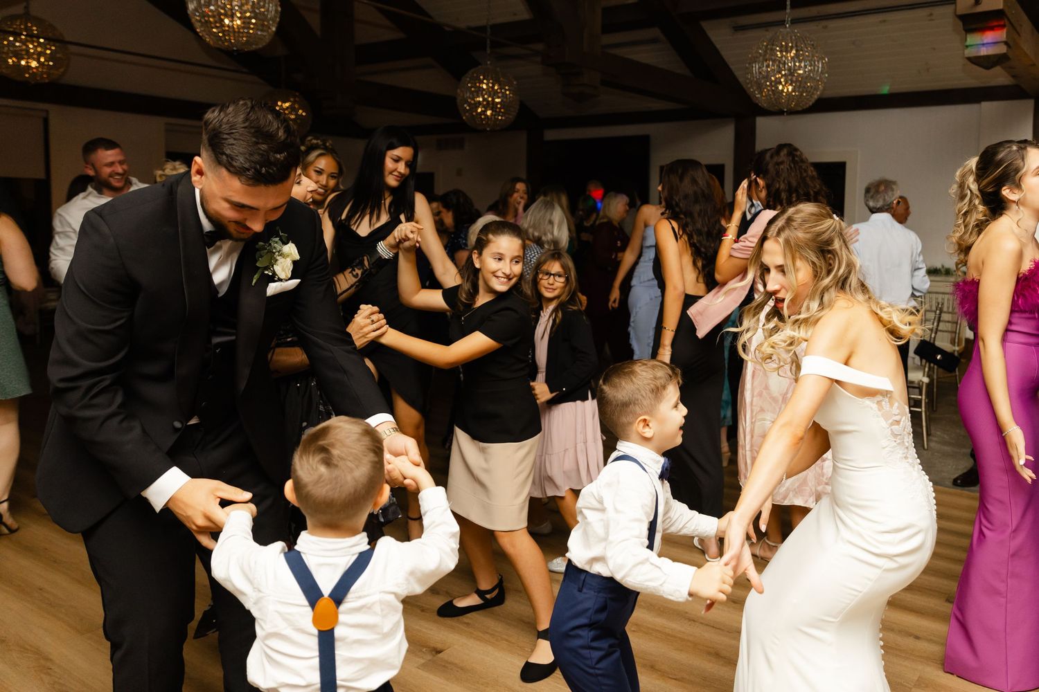 Wedding reception dance floor scene with guests dancing and celebrating together.