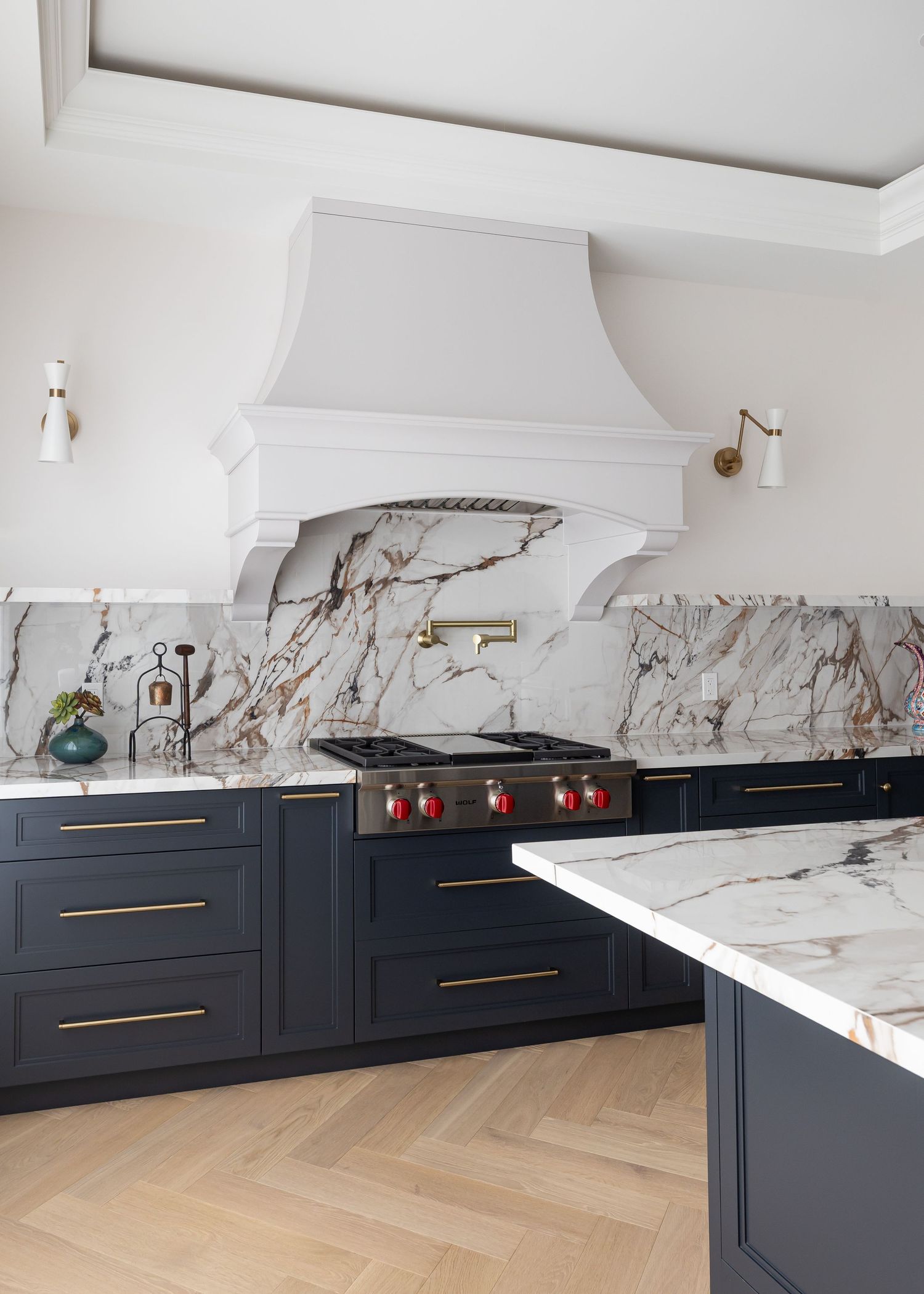 Luxurious kitchen featuring dark cabinets, marble backsplash, and brass hardware.