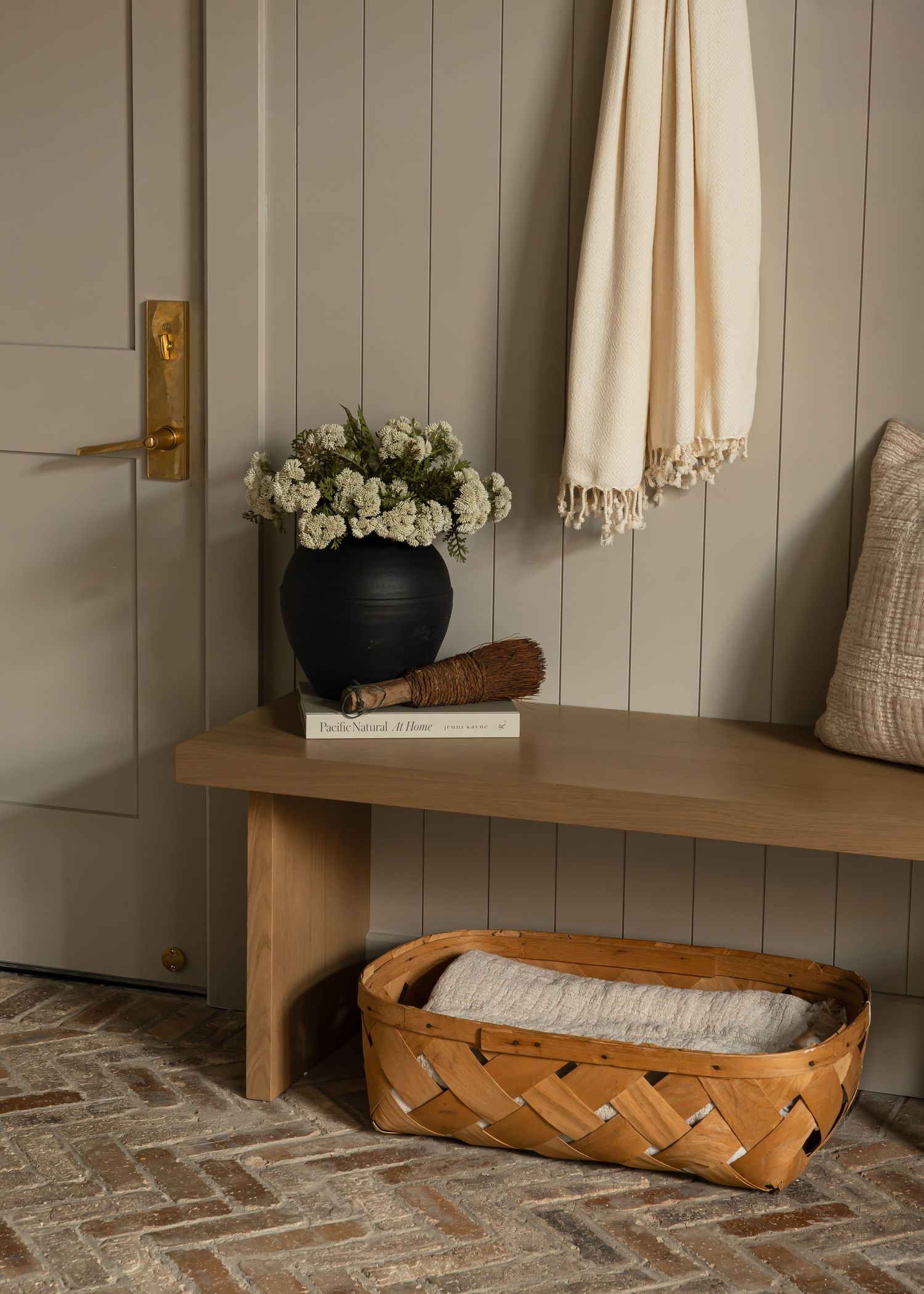 Built-in wooden bench with leather cushion and cream throw pillows in neutral space.
