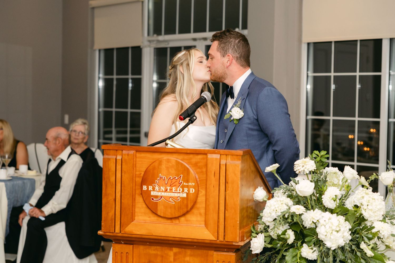 Wedding reception venue decorated with white floral arrangements and wooden piano.