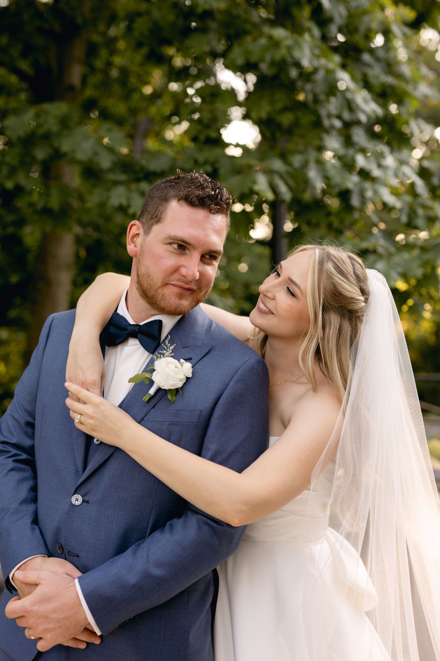 Romantic outdoor wedding portraits showing tender moments between newlyweds in a navy suit and white dress.