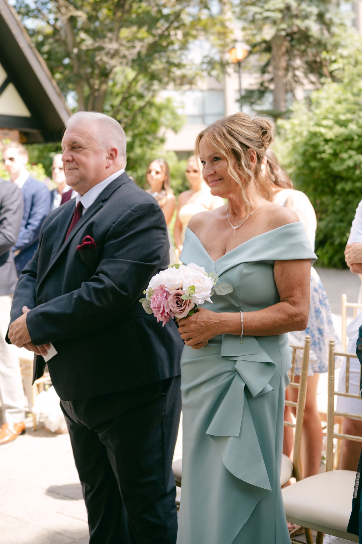 Wedding guests in formal attire share emotional moments during outdoor celebration.