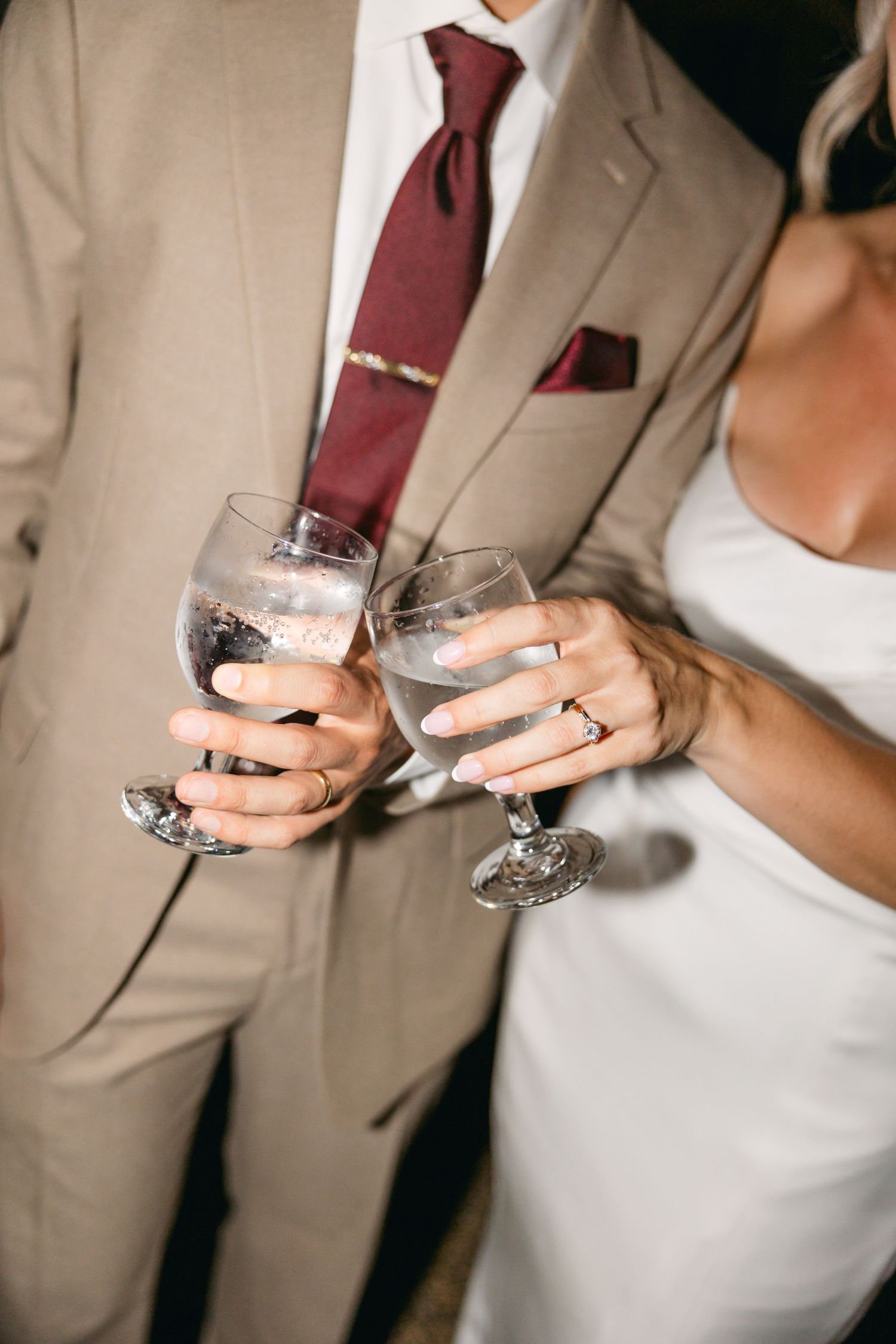 Close-up of champagne glasses being held at a formal wedding celebration.