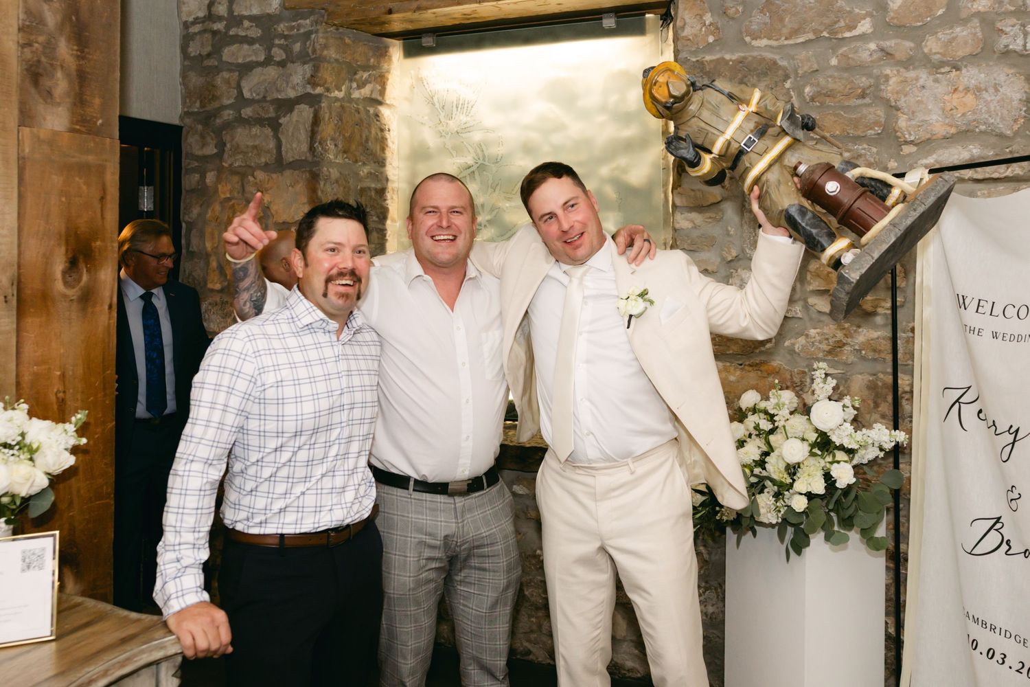 Group celebration shot at rustic wedding venue with stone walls and wooden beams.