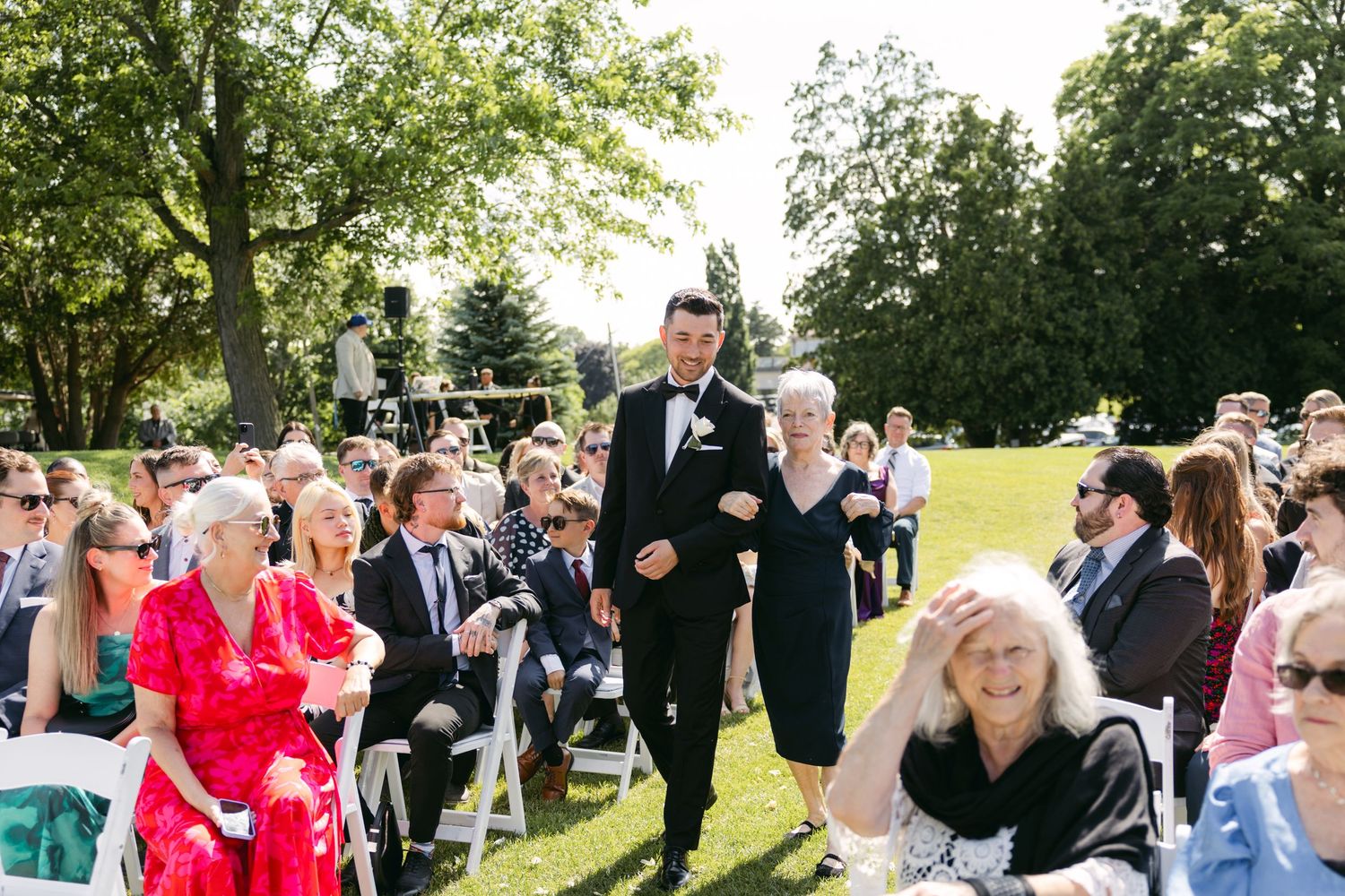 Wedding guests mingle and celebrate during an outdoor reception on a sunny day.