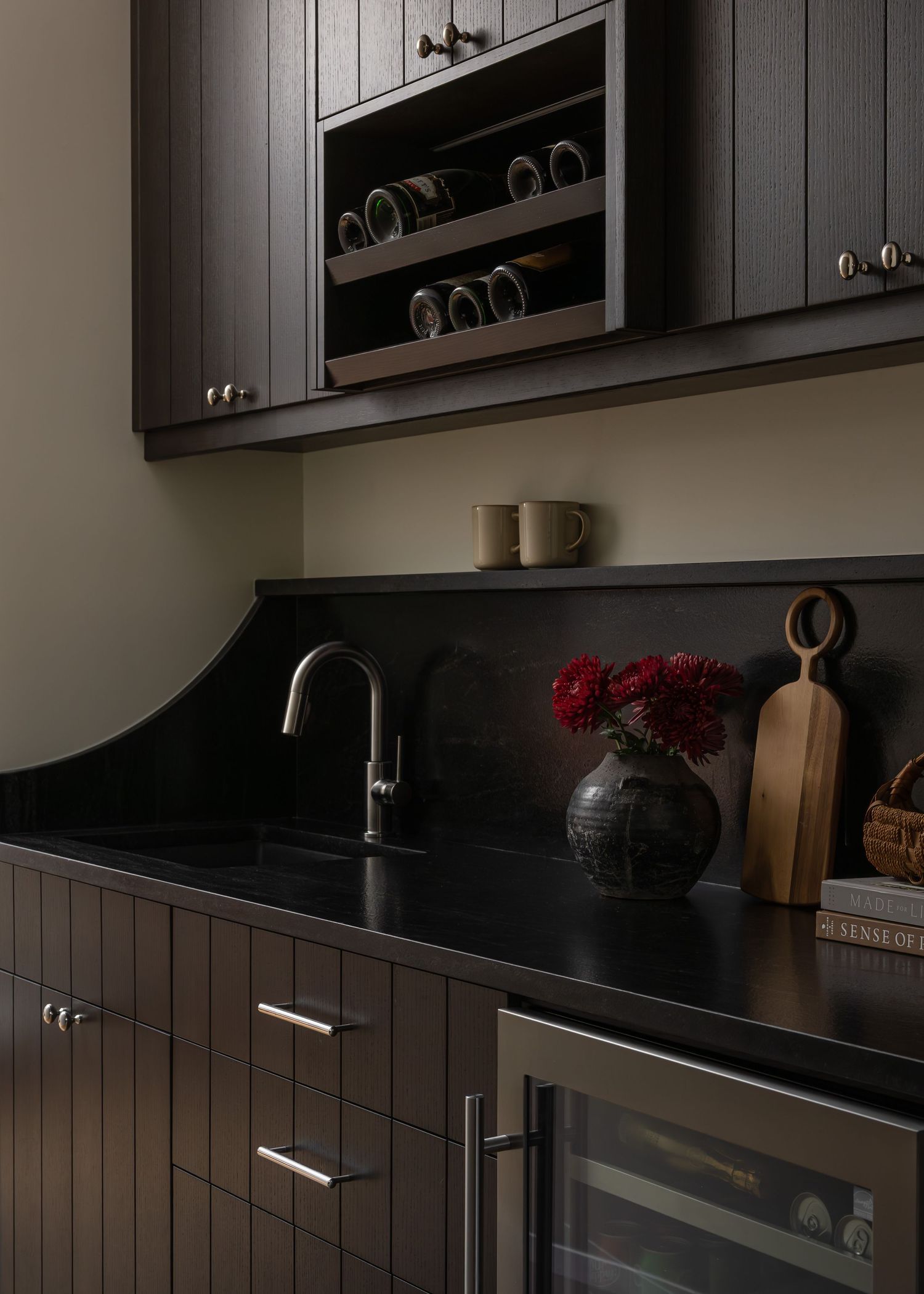 Dark wood kitchen storage area with wine rack and decorative accents.