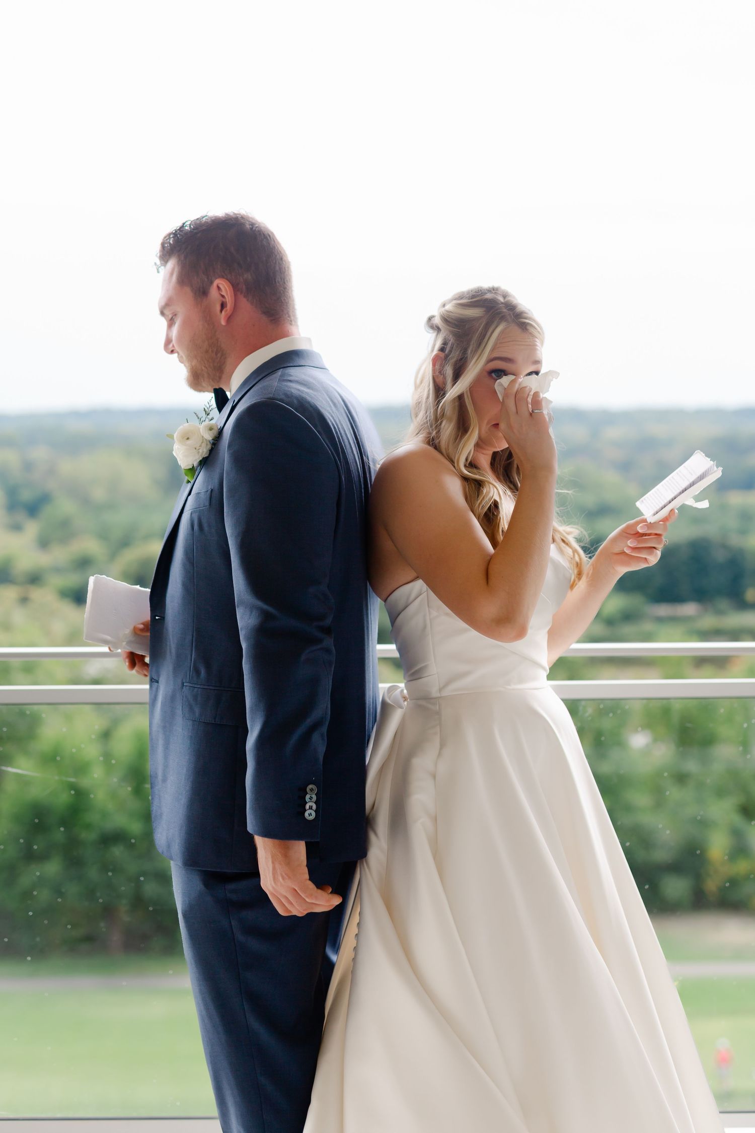 Couple reads private letters while standing back-to-back on scenic balcony.
