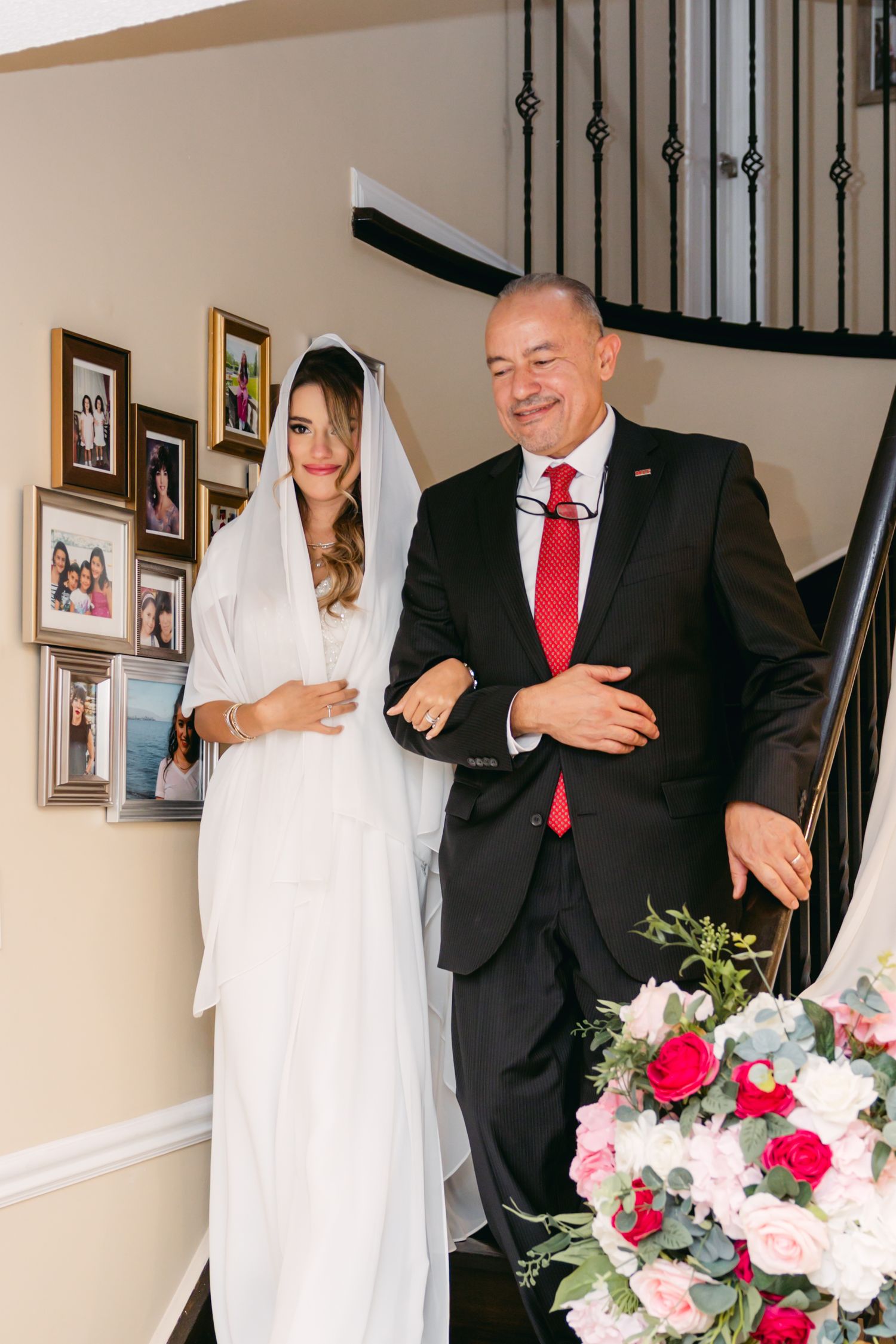 Wedding photos captured on an elegant staircase with pink and white floral decorations.
