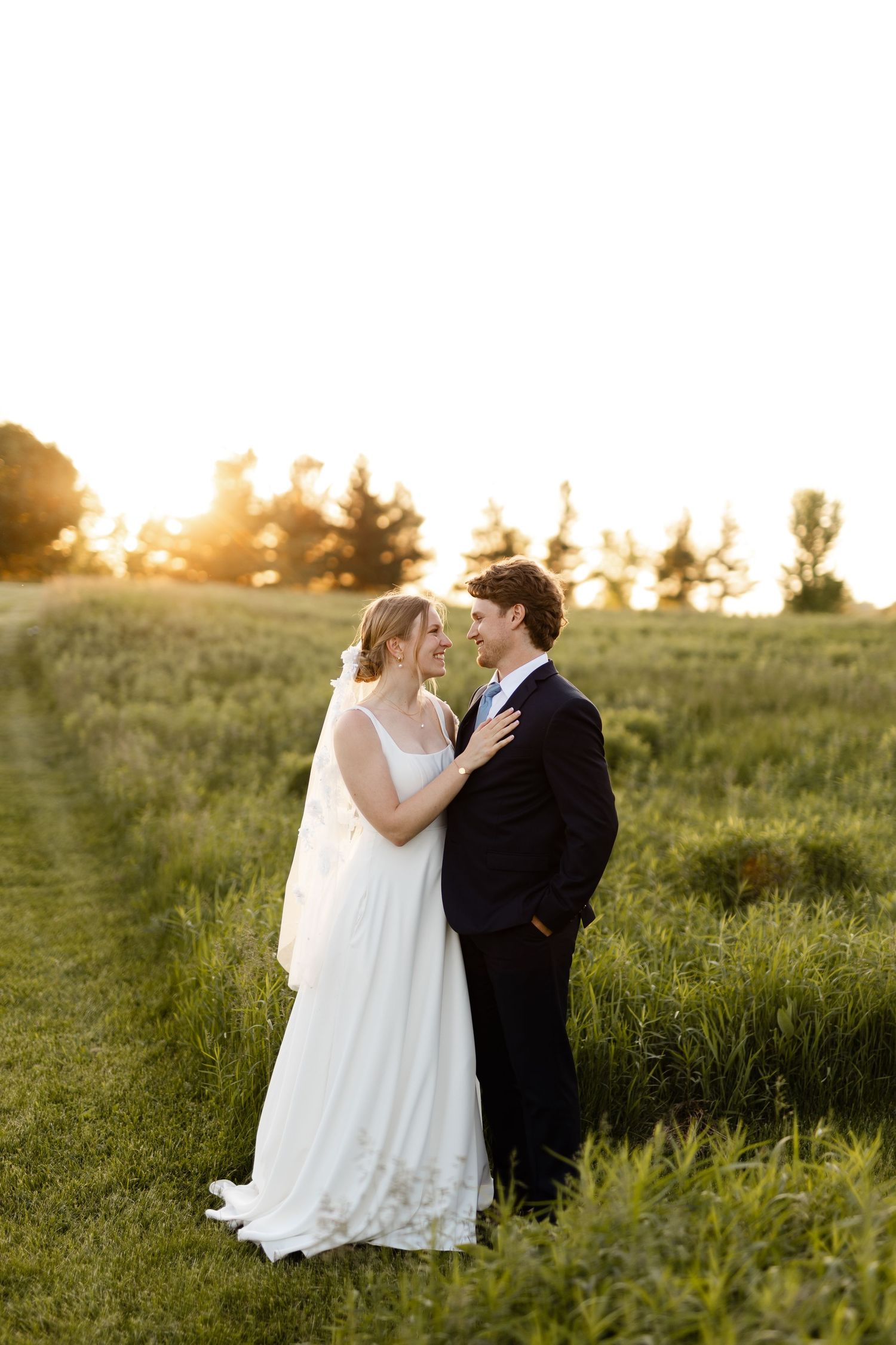 A romantic wedding photo session in a golden meadow at sunset.