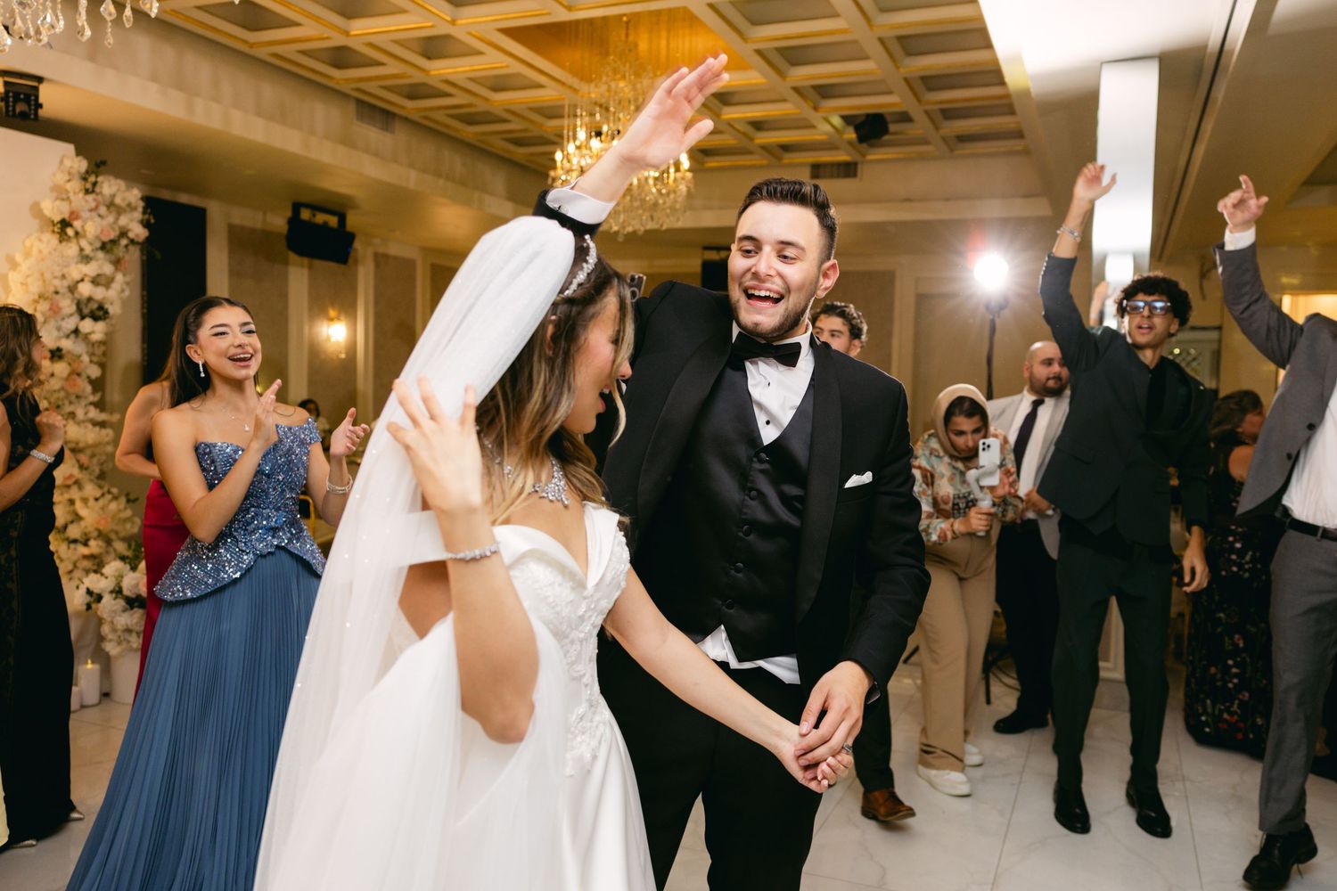 Newlyweds share a romantic dance moment during their wedding reception under crystal chandeliers.