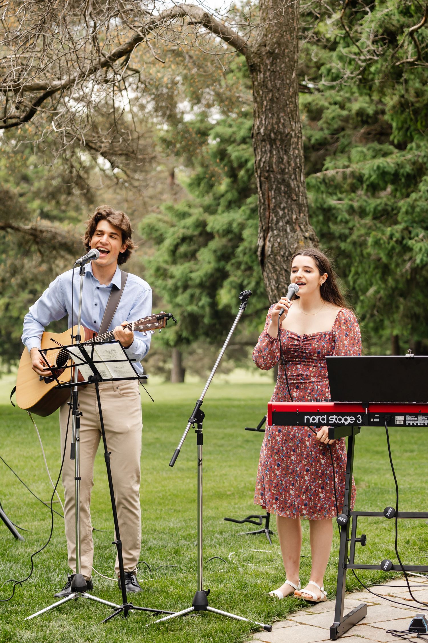 Musicians performing at outdoor wedding with acoustic guitar and keyboard setup.