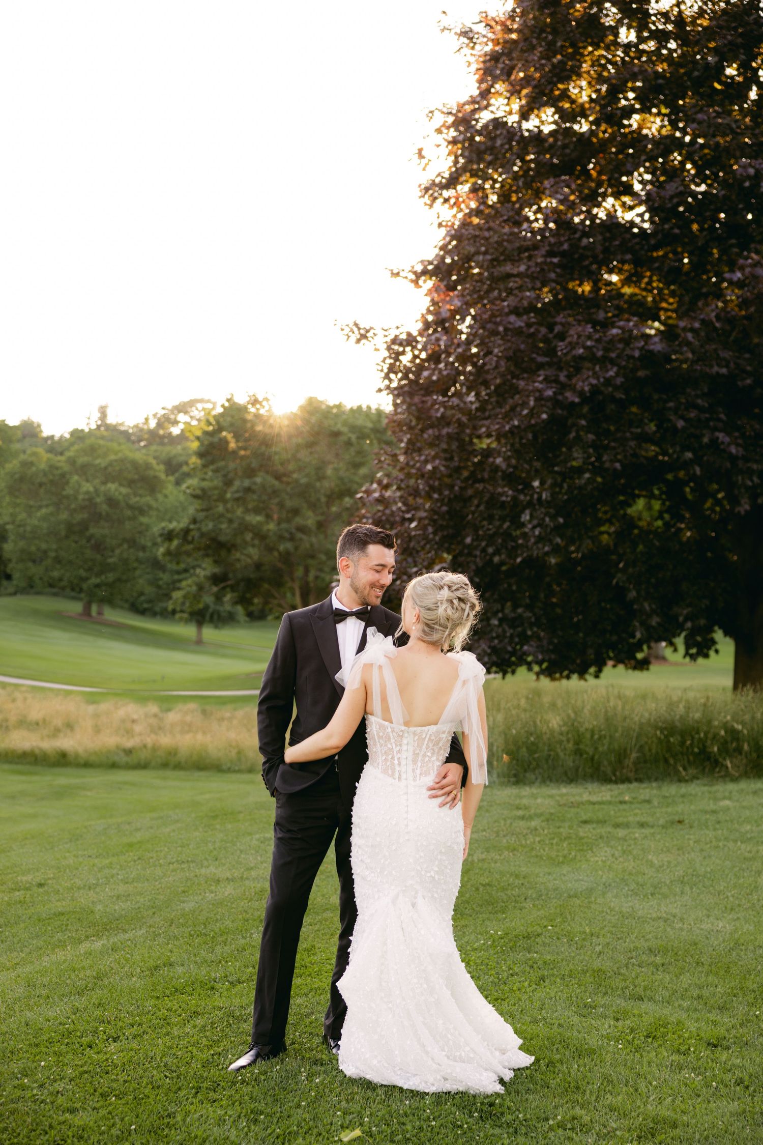 Romantic wedding portraits captured on a rolling green golf course at sunset.