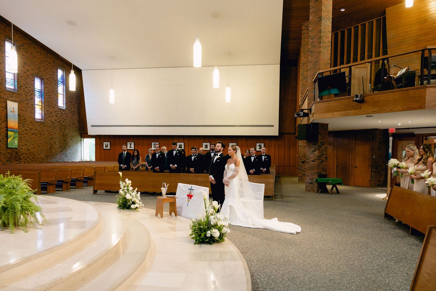 Wedding ceremony at church altar with bride, groom, and wedding party gathered before guests.