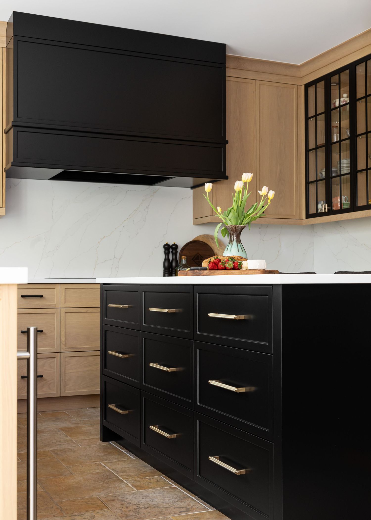 Contemporary kitchen showcasing black drawer fronts with metallic handles against warm wood cabinetry.