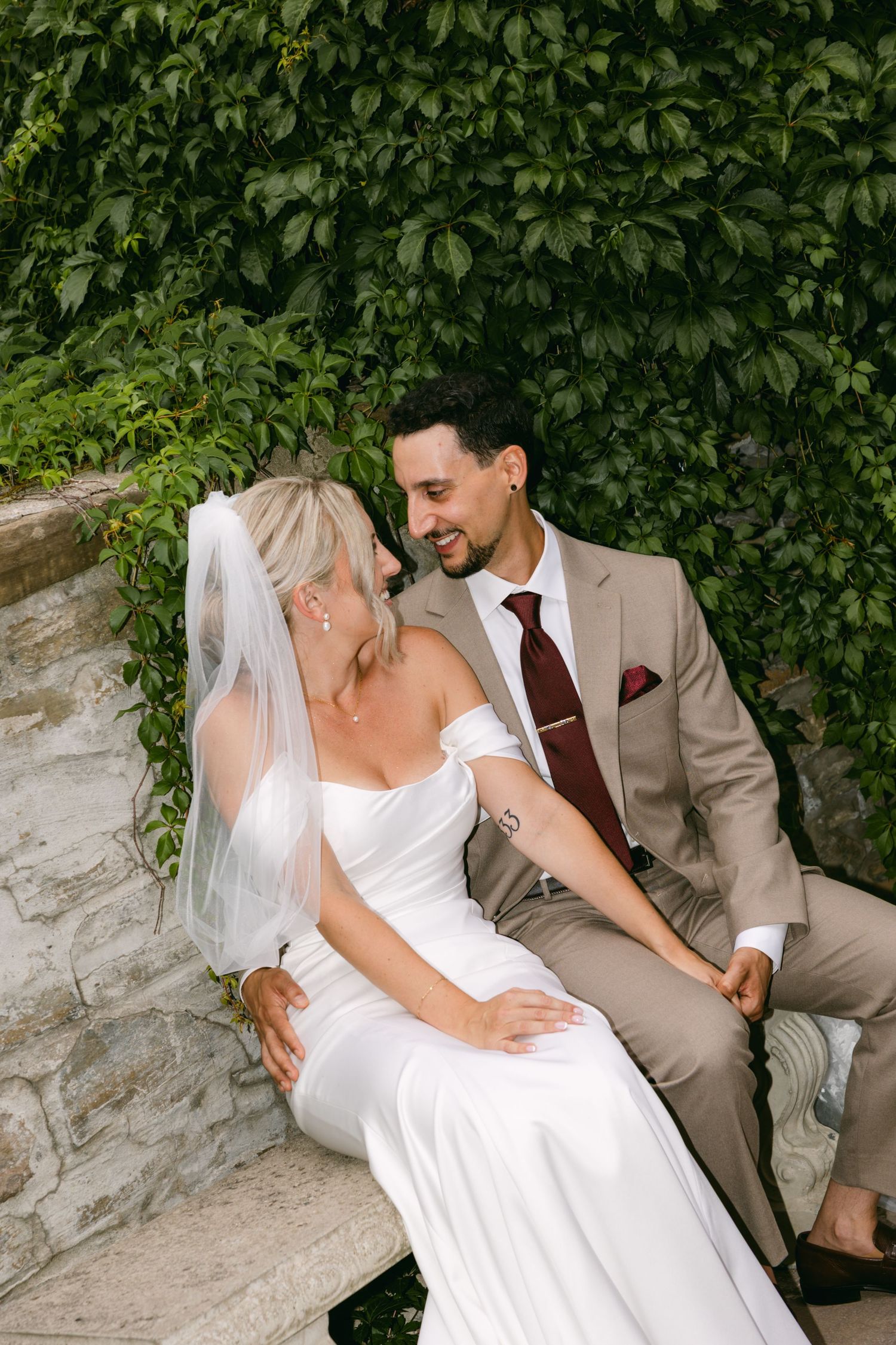 Intimate wedding portraits captured against an ivy-covered stone wall.
