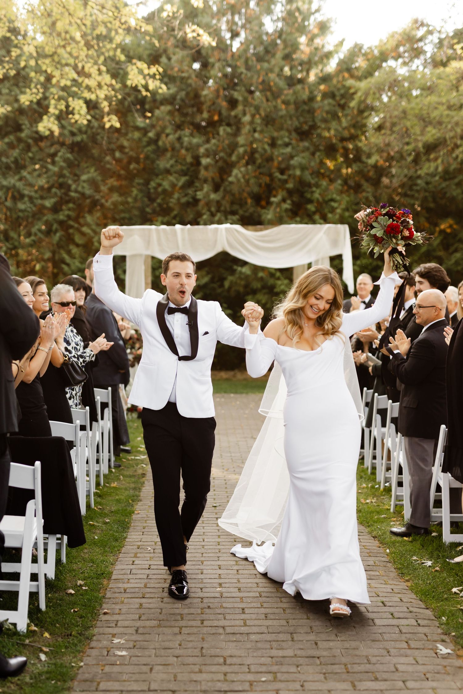 Joyful wedding recessional down stone pathway with guests celebrating on both sides.