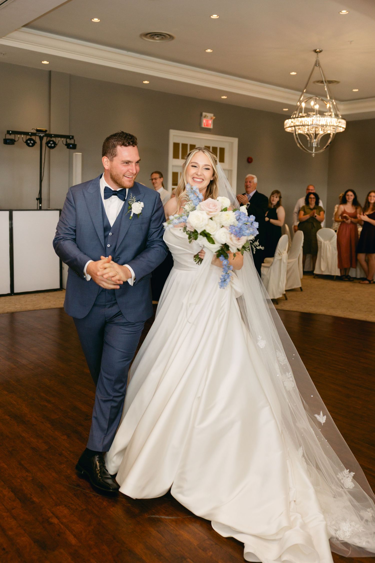 A couple shares a joyful moment during their wedding reception in an elegant ballroom setting.