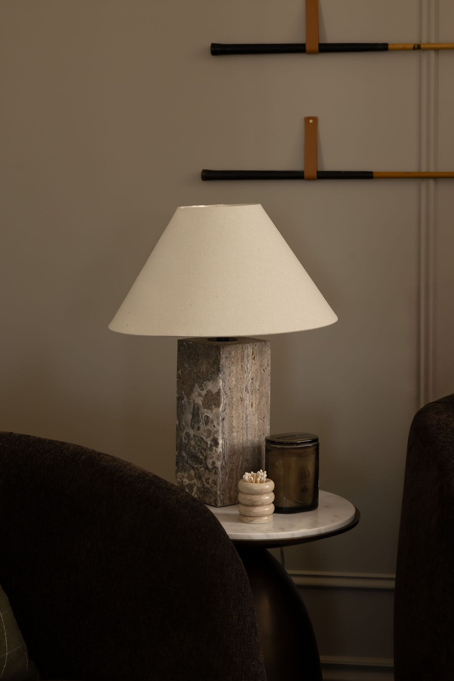 Minimalist corner featuring white dome lamp shade and dark upholstered furniture.