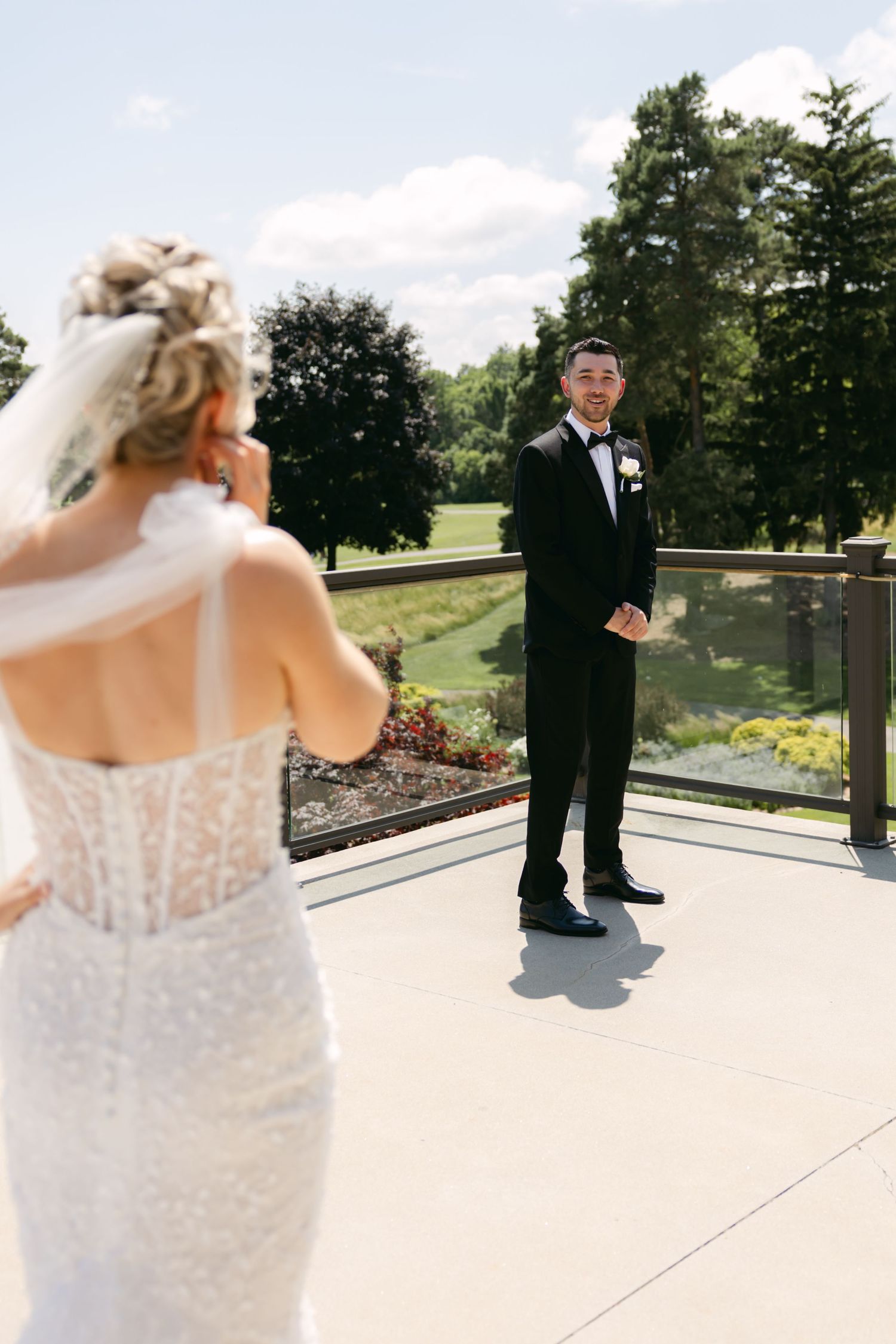 Elegant wedding dress details shown on outdoor terrace with golf course backdrop.