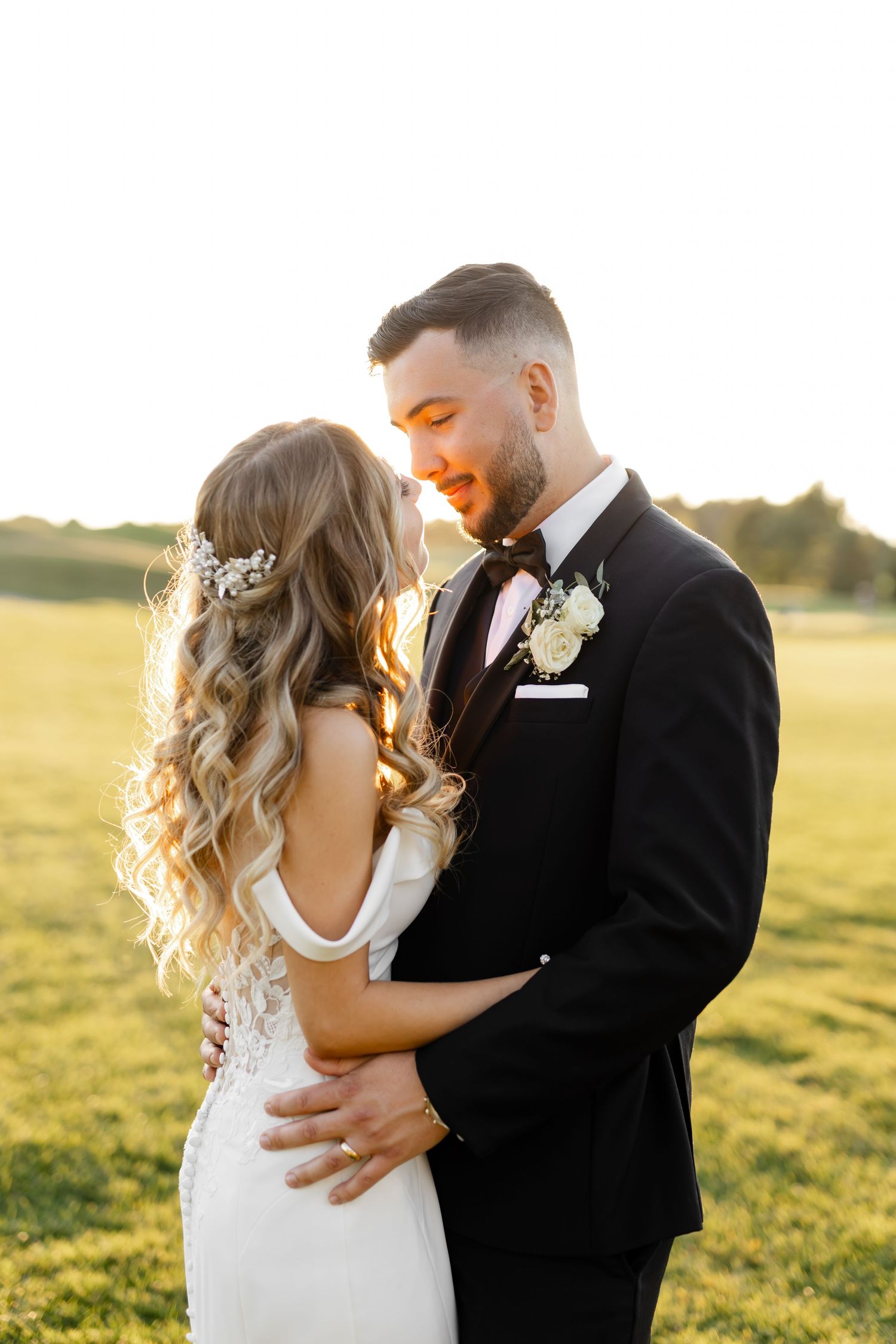 Romantic sunset portraits of newlyweds embracing in a golden field.