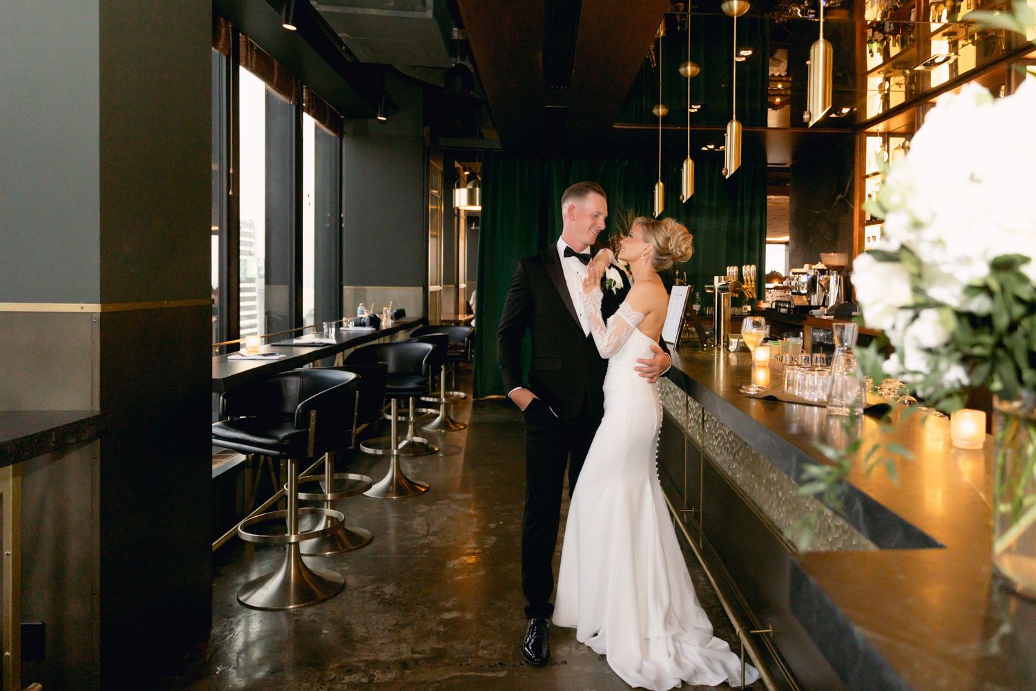 Bride and groom share a romantic moment together at a sleek, moody upscale bar venue.