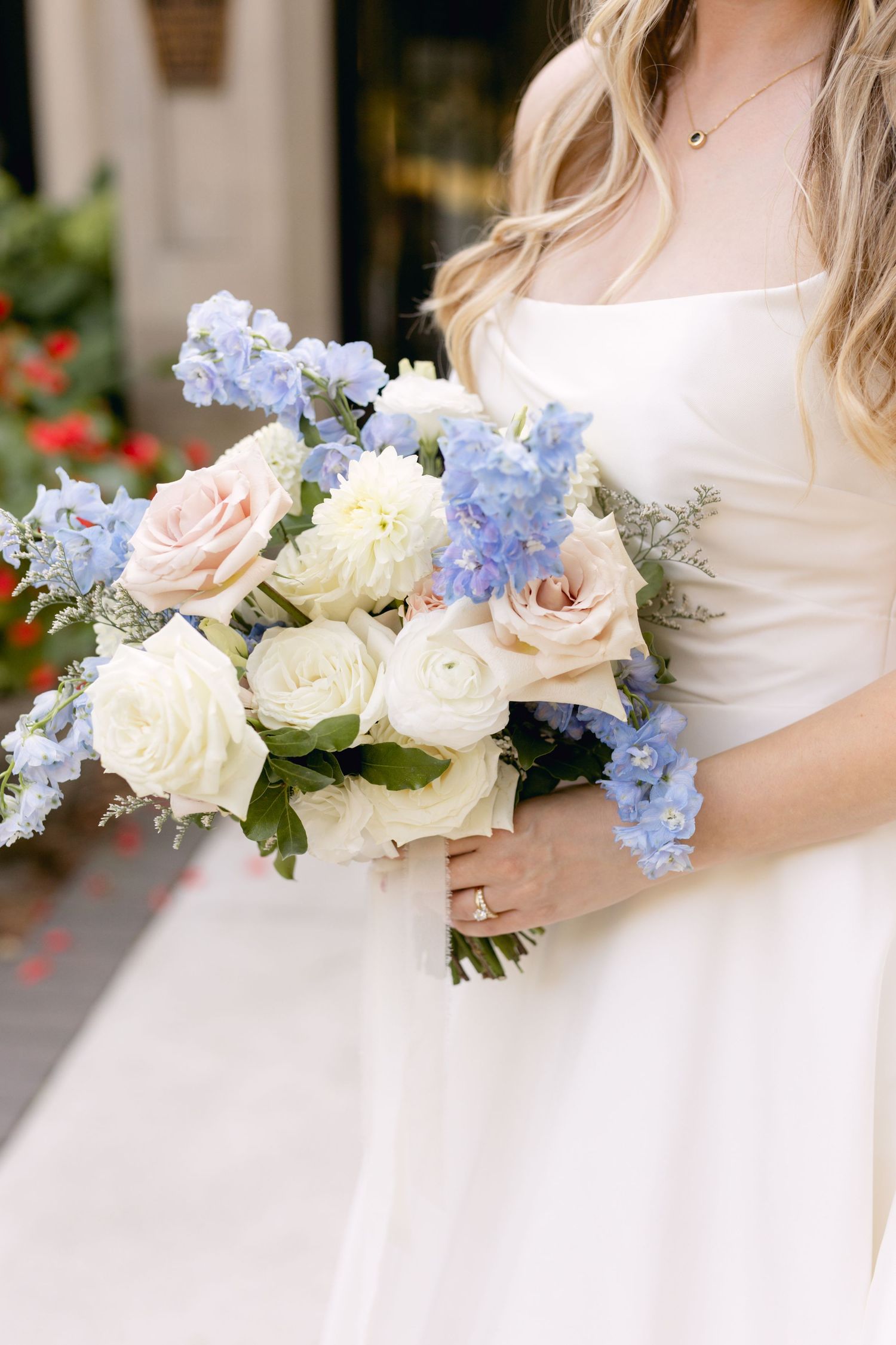 Elegant bridal bouquet featuring white roses and light blue delphinium flowers.