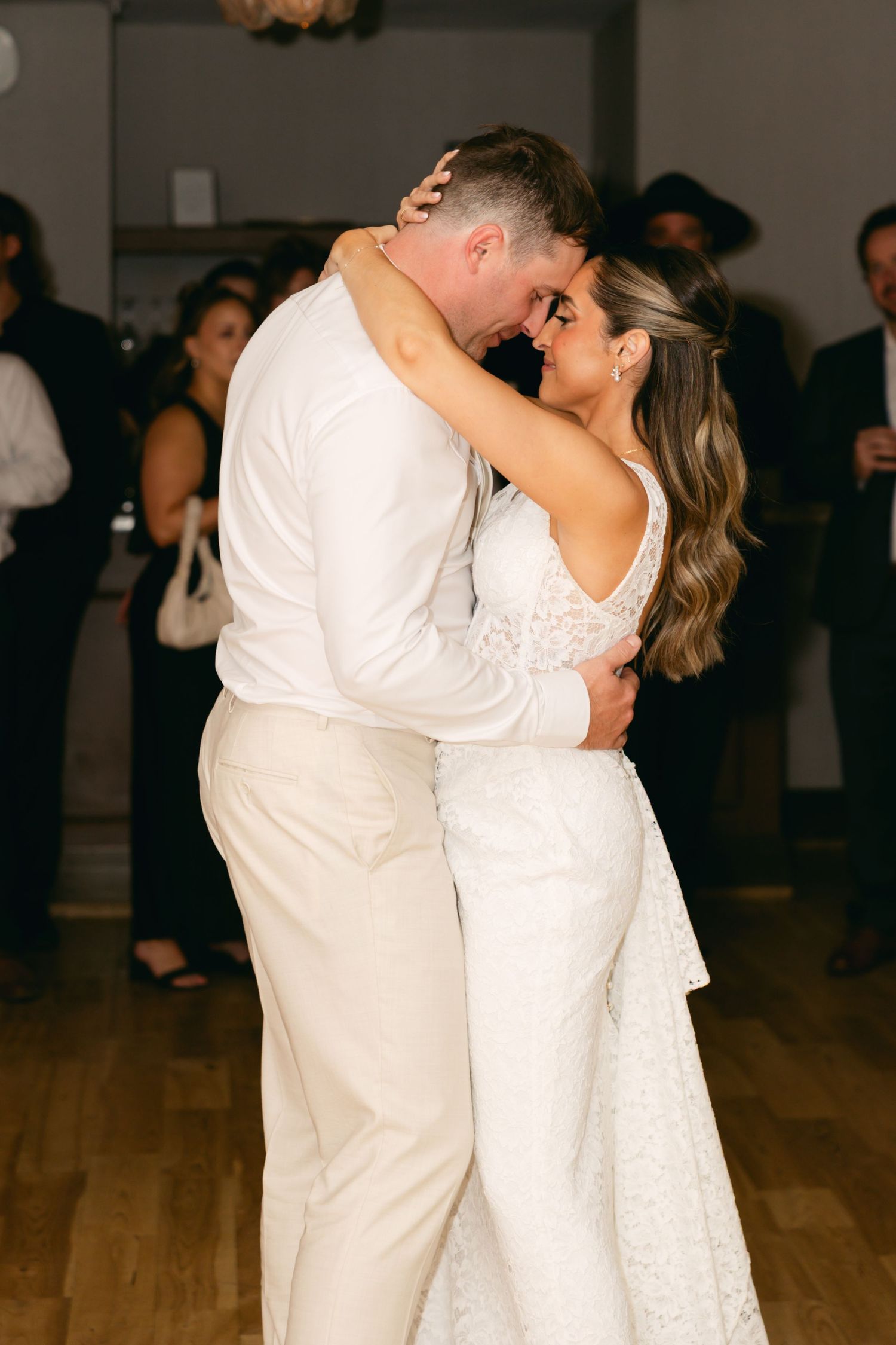 A romantic first dance moment captured at a wedding reception on a wooden dance floor.