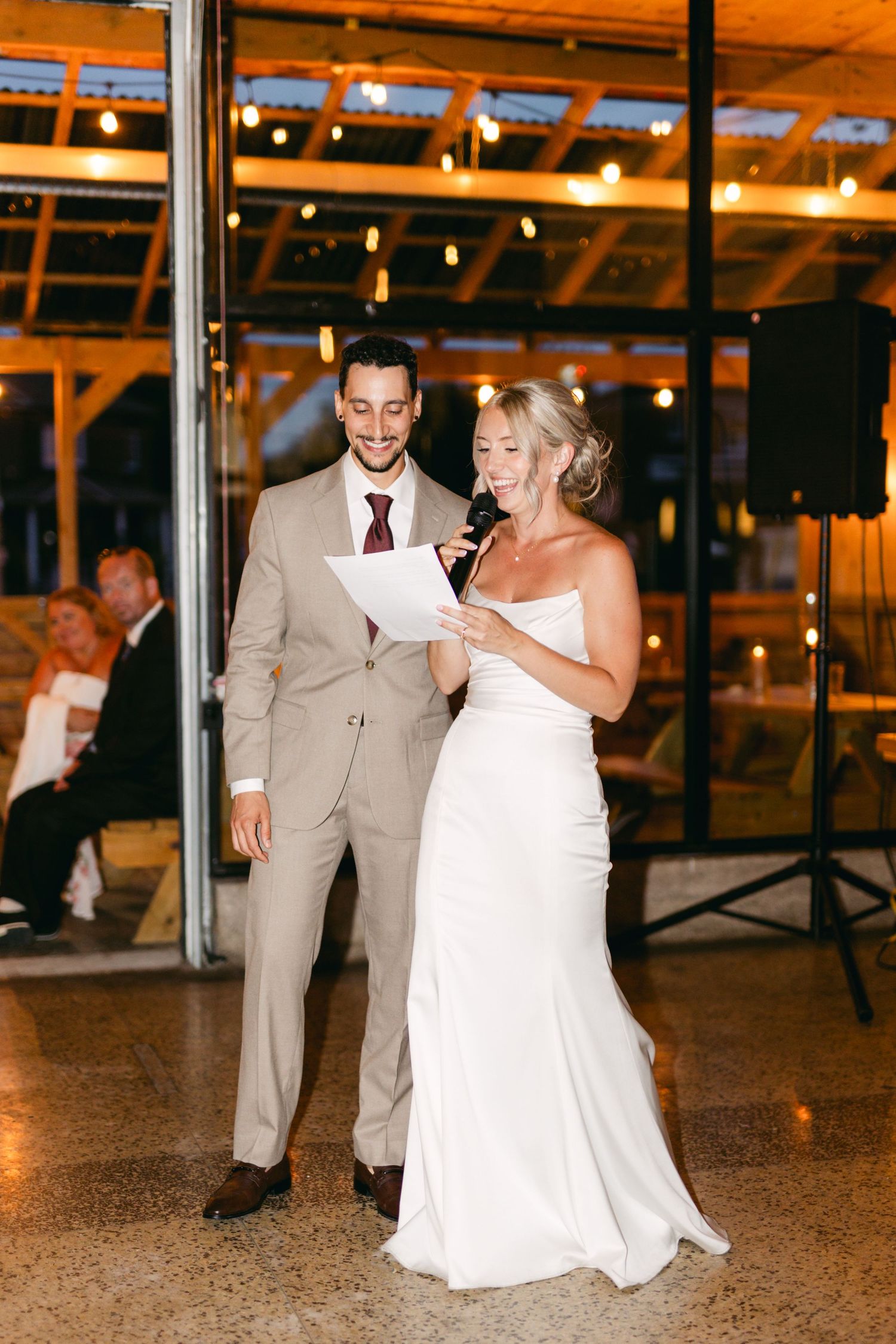 Wedding celebration on dance floor with guests in formal attire under string lights.