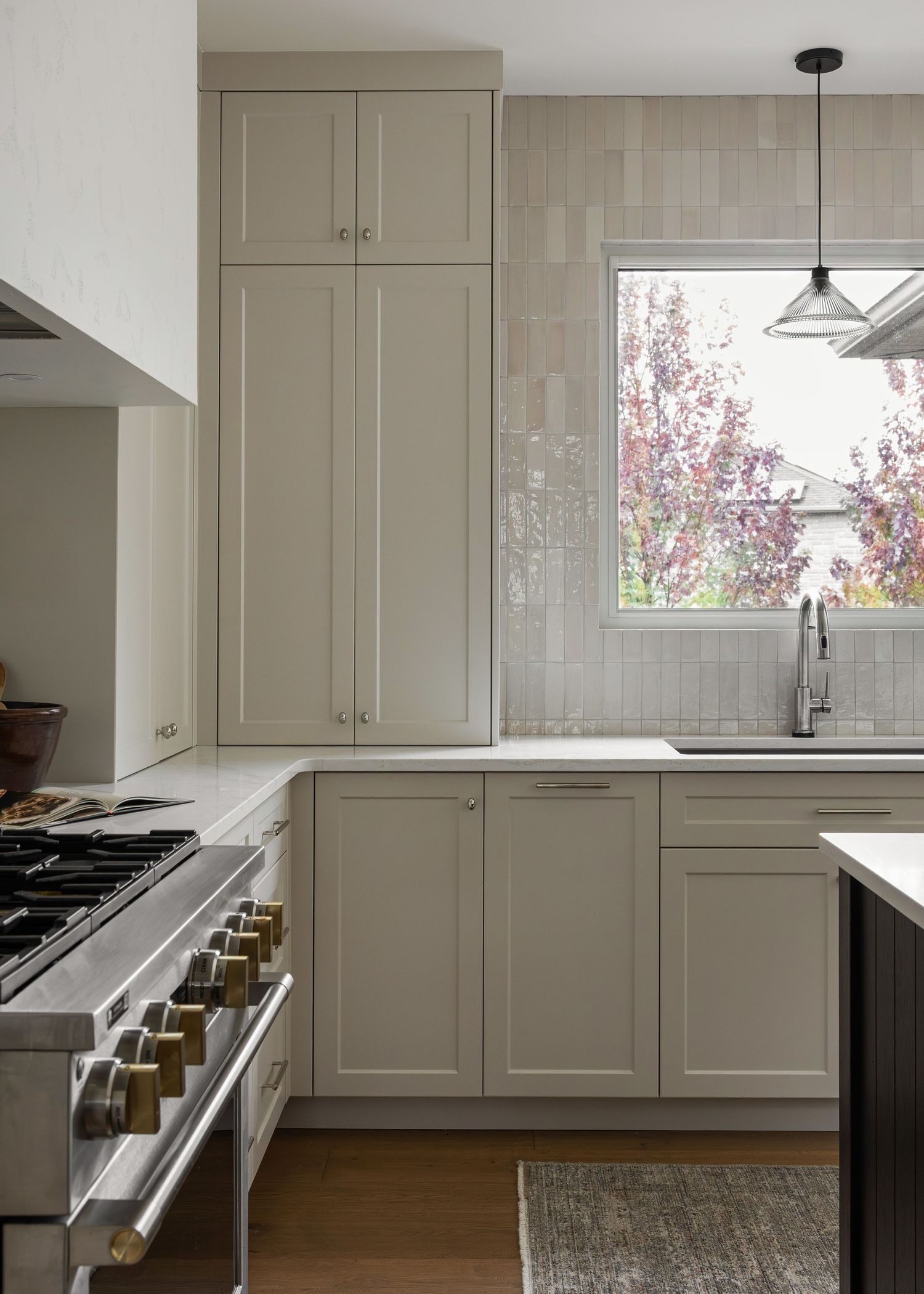 Light-filled kitchen with beige cabinets, hardwood floors, and stainless steel appliances.