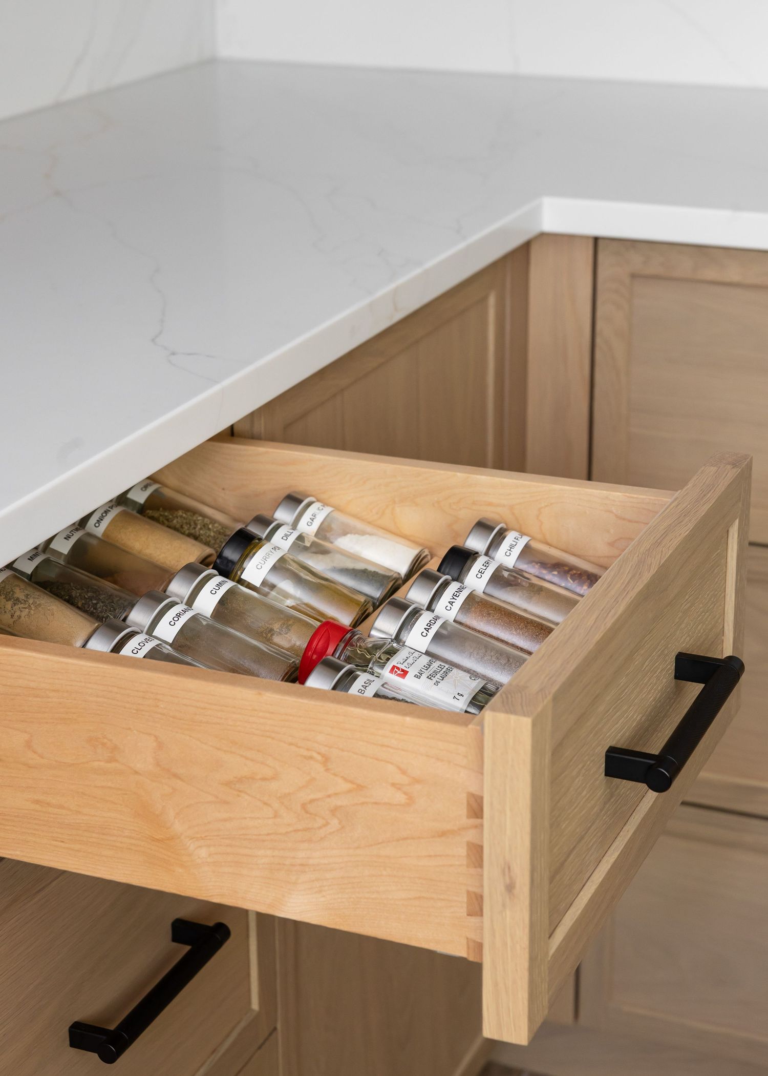 Angled drawer organizer system for spice storage with black handles.