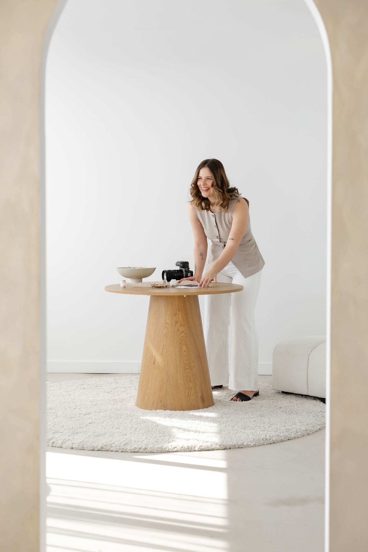 Bright minimalist room with wooden pedestal table and arched doorway.