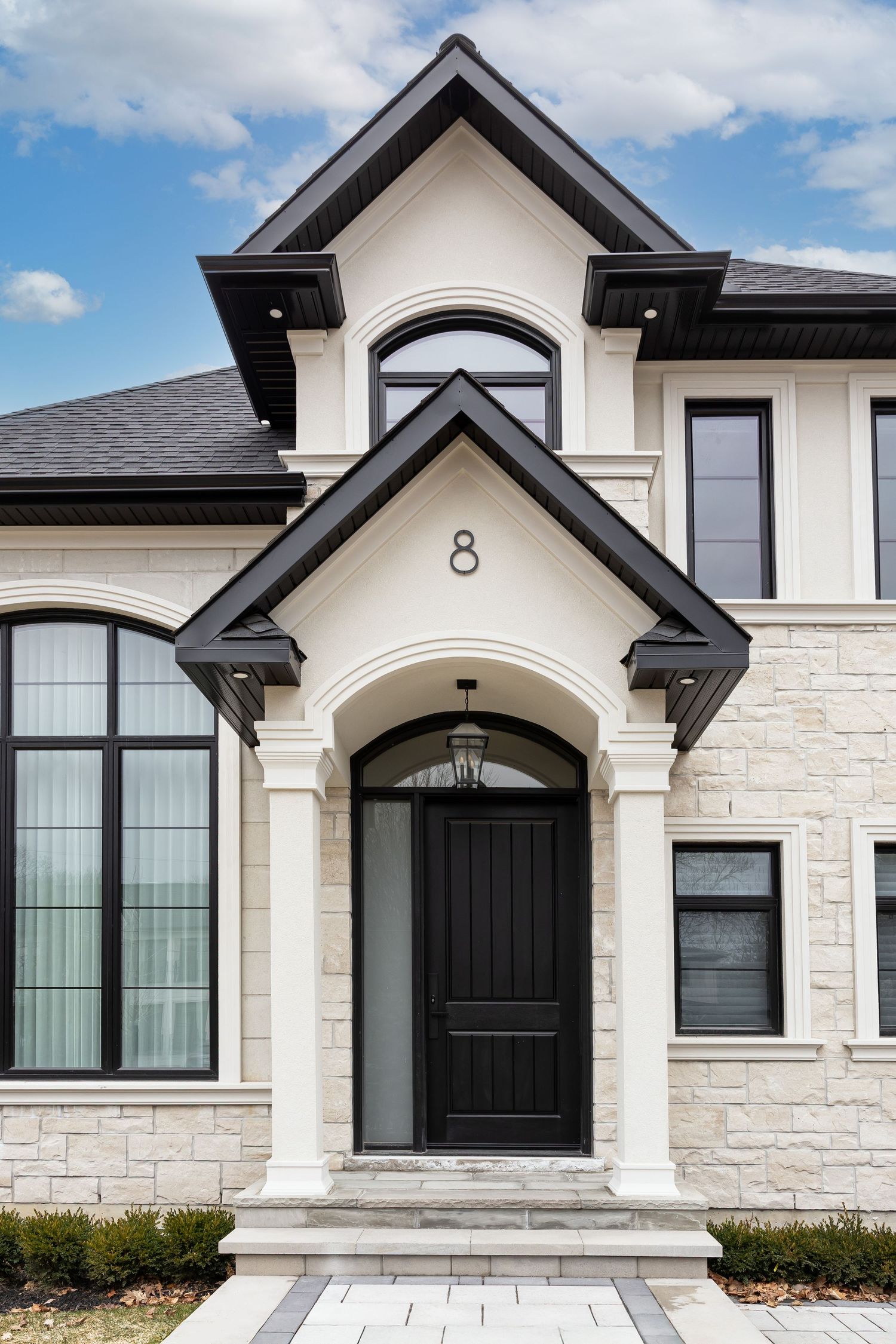Elegant stone house entrance with black door and architectural details featuring number 8.
