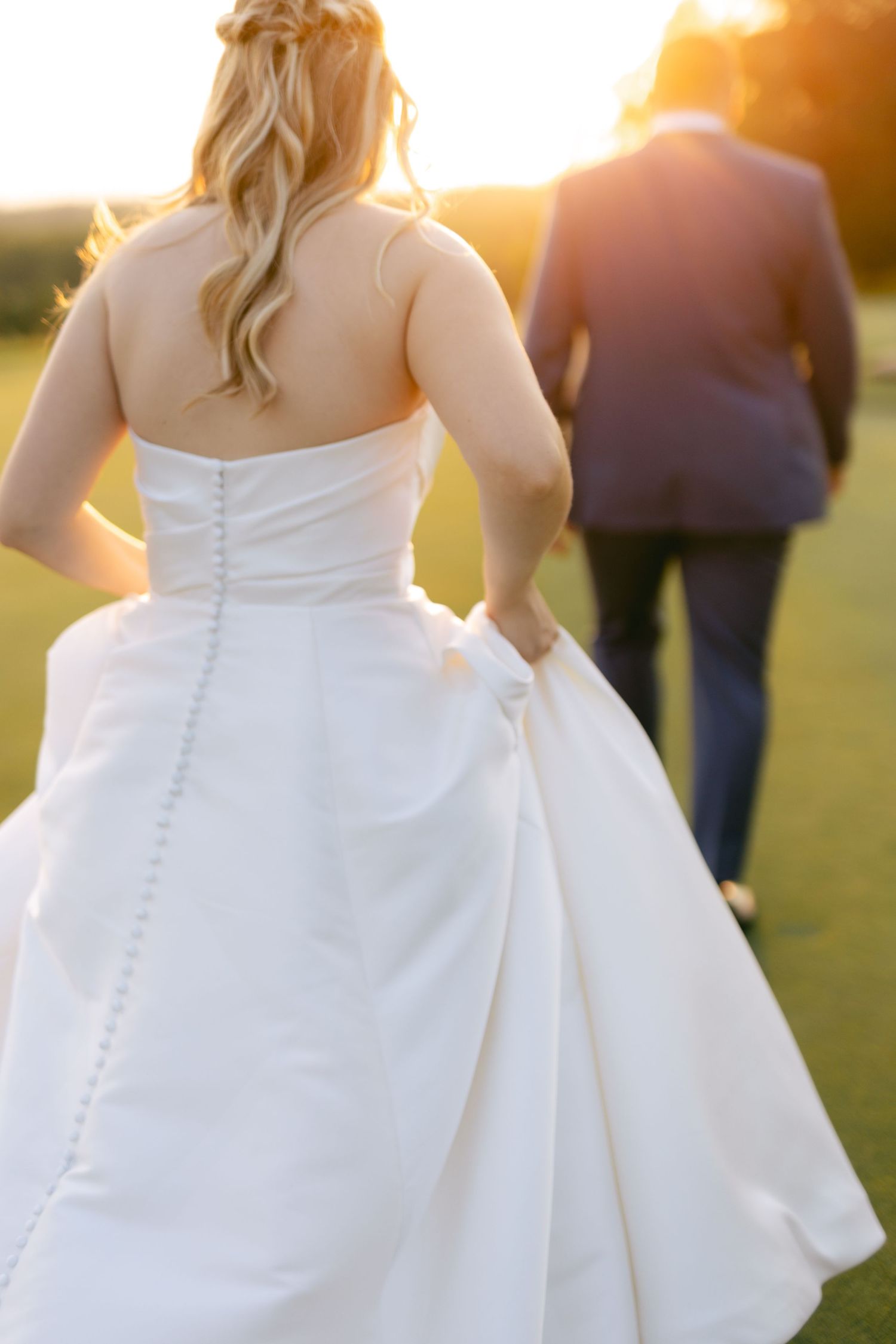 Close-up details of white wedding dress buttons and fabric during outdoor sunset photography.