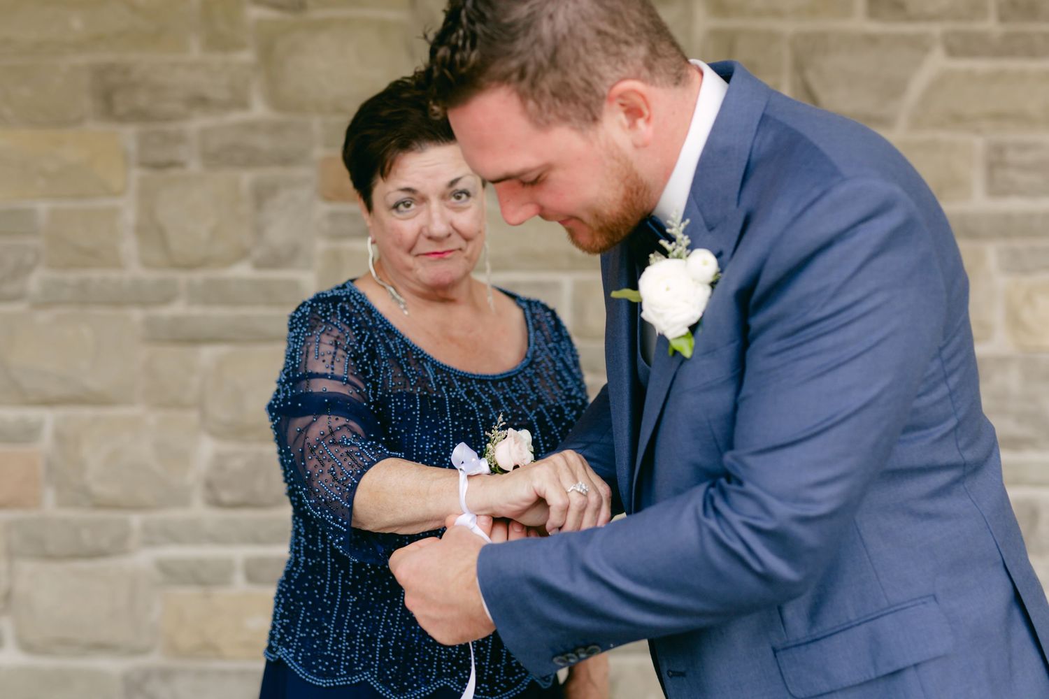 A touching moment as a corsage is pinned on during wedding preparations.
