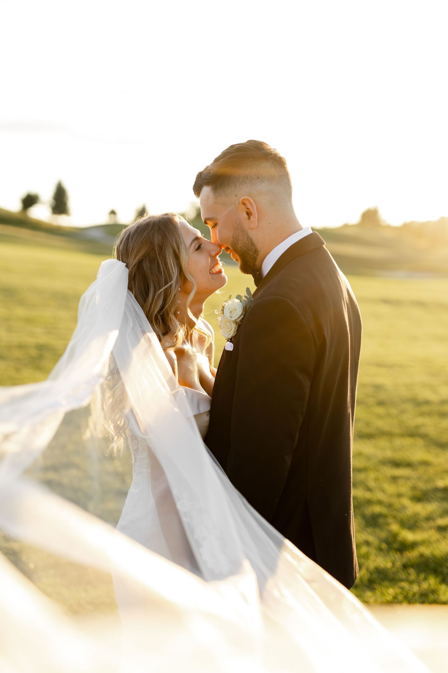 Intimate wedding portraits captured during golden hour with bride's veil flowing in the breeze.