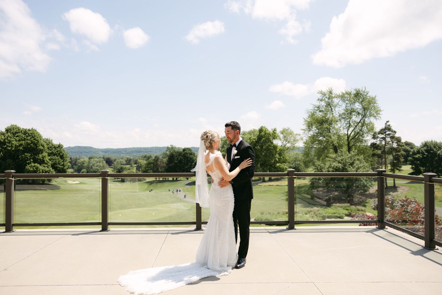 Panoramic view of wedding couple on terrace with scenic landscape in background.