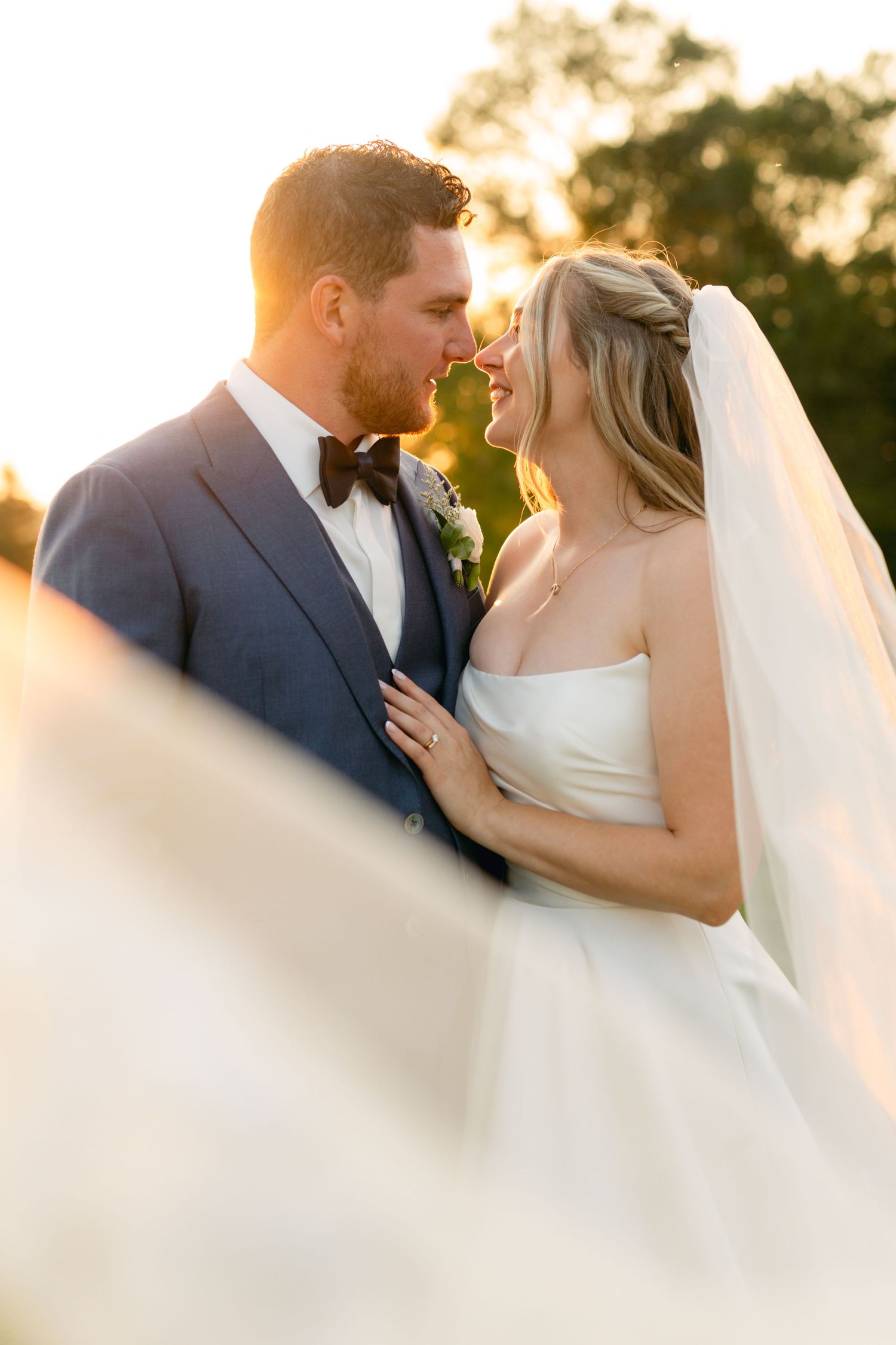 A romantic sunset moment captured between newlyweds with golden light streaming through their veil.