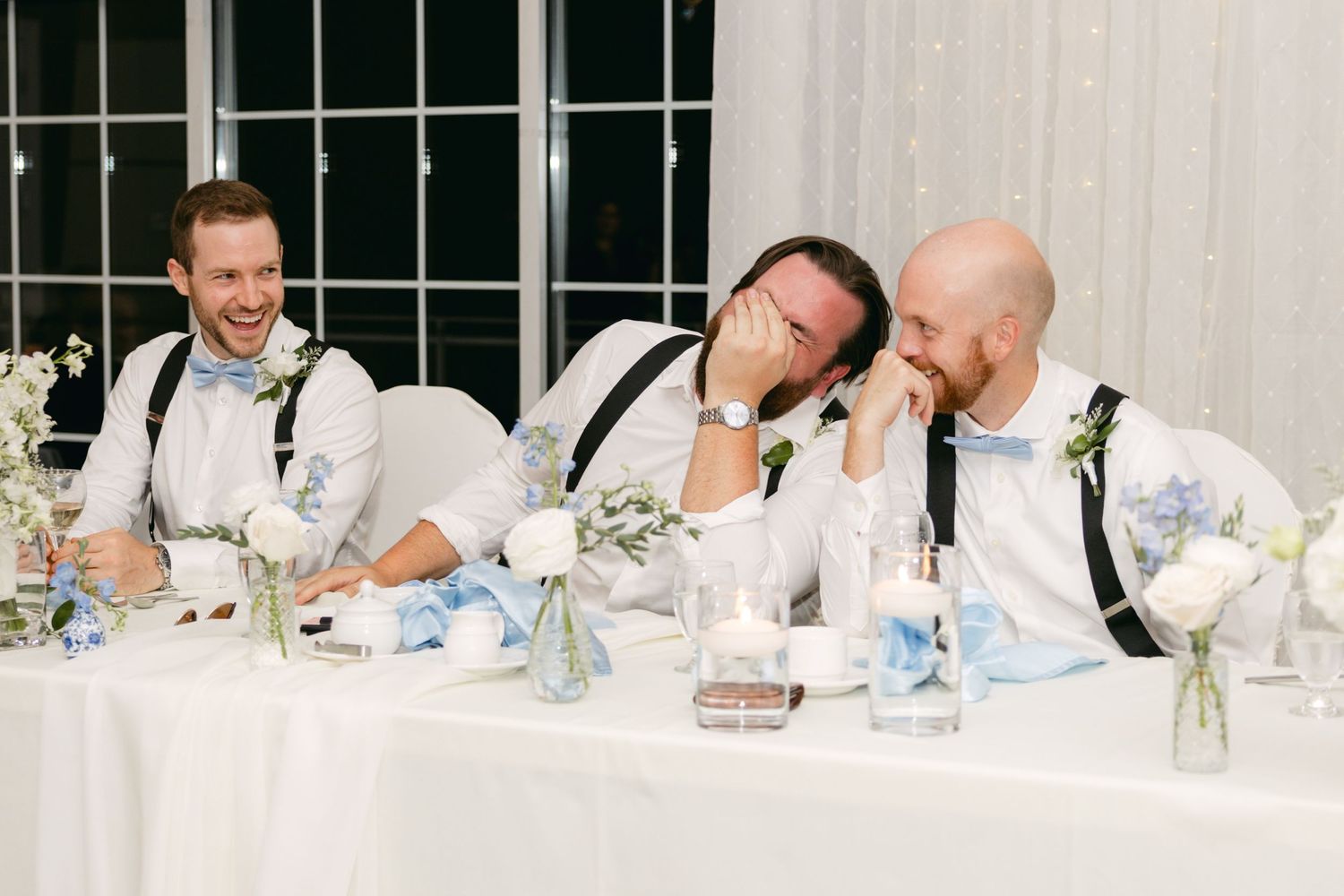 Wedding reception guests share laughter during dinner speeches.