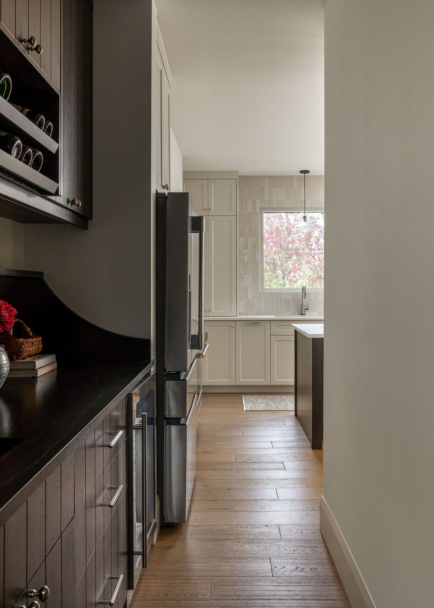 Hallway with dark wood floors and built-in storage leading to bright kitchen area.