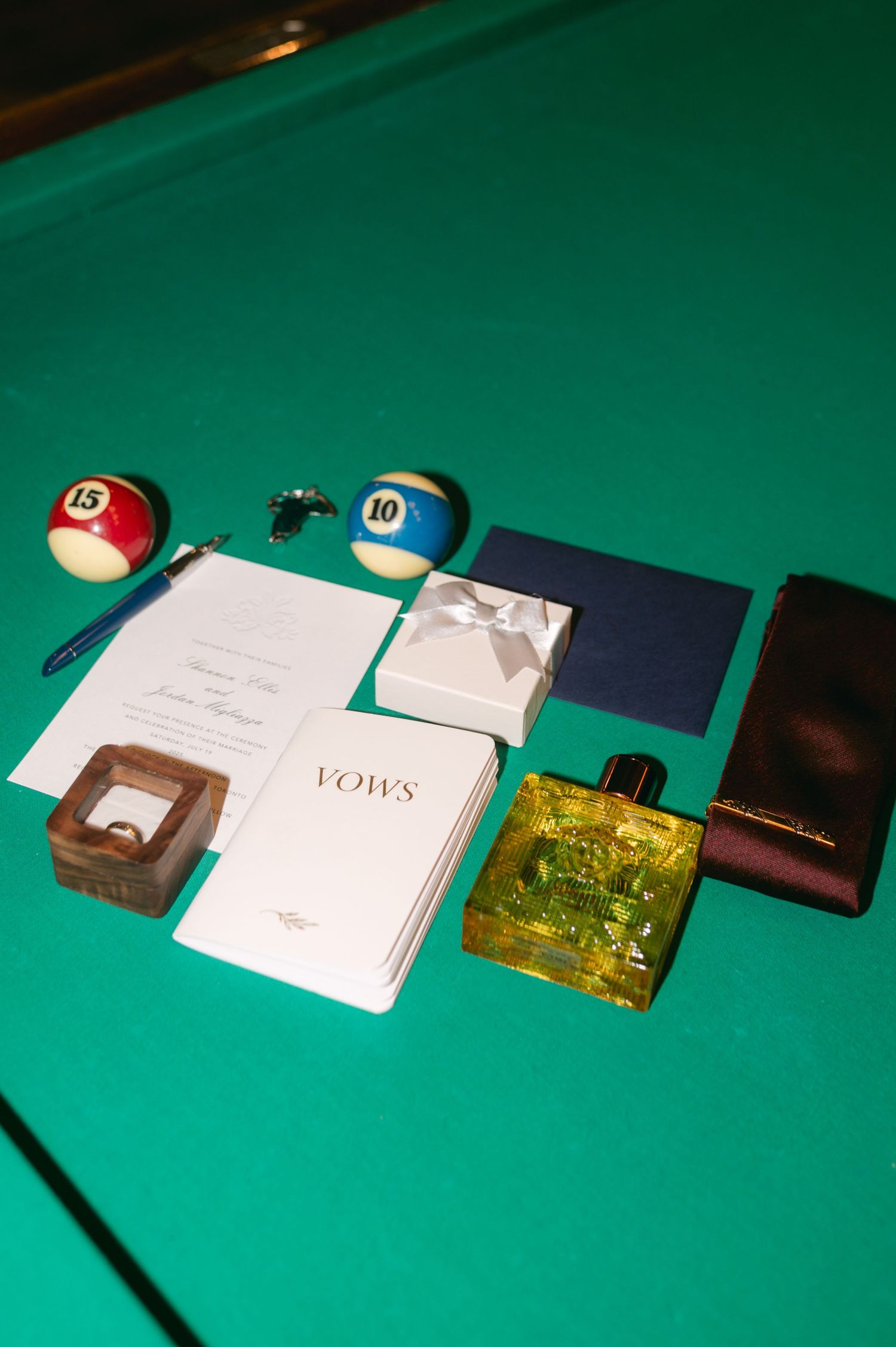 Wedding details including vow books and personal items arranged on green felt surface.