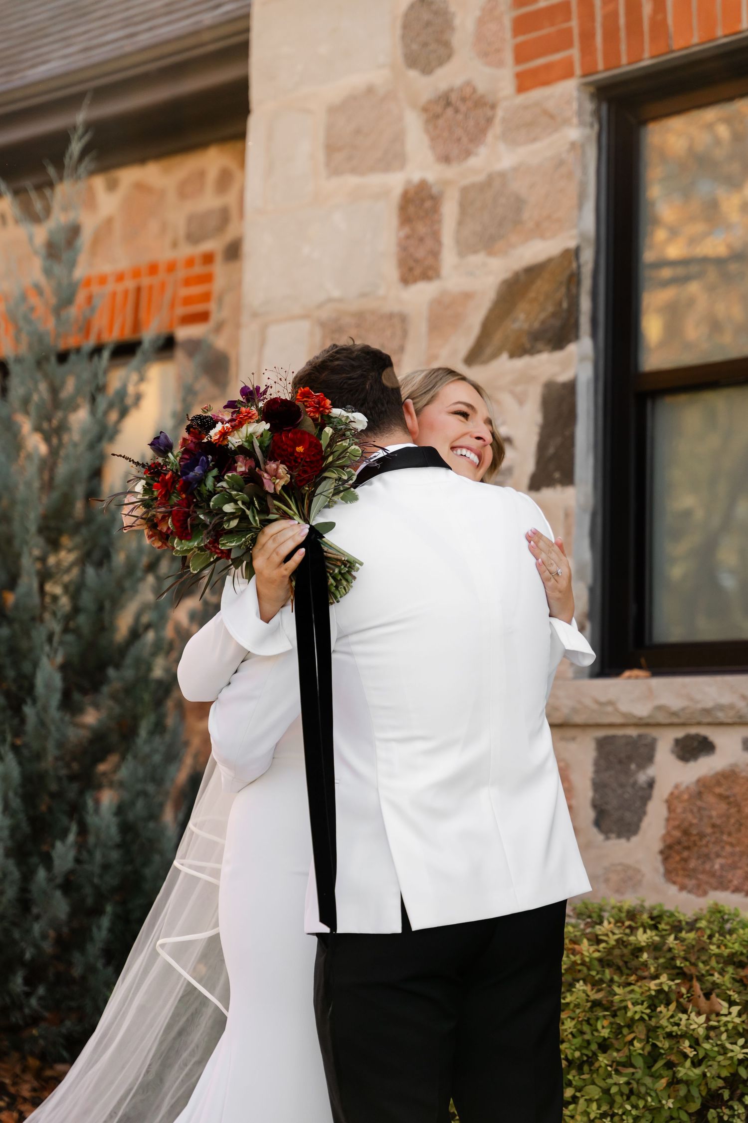 A tender embrace between newlyweds during their first look with autumn foliage in background.
