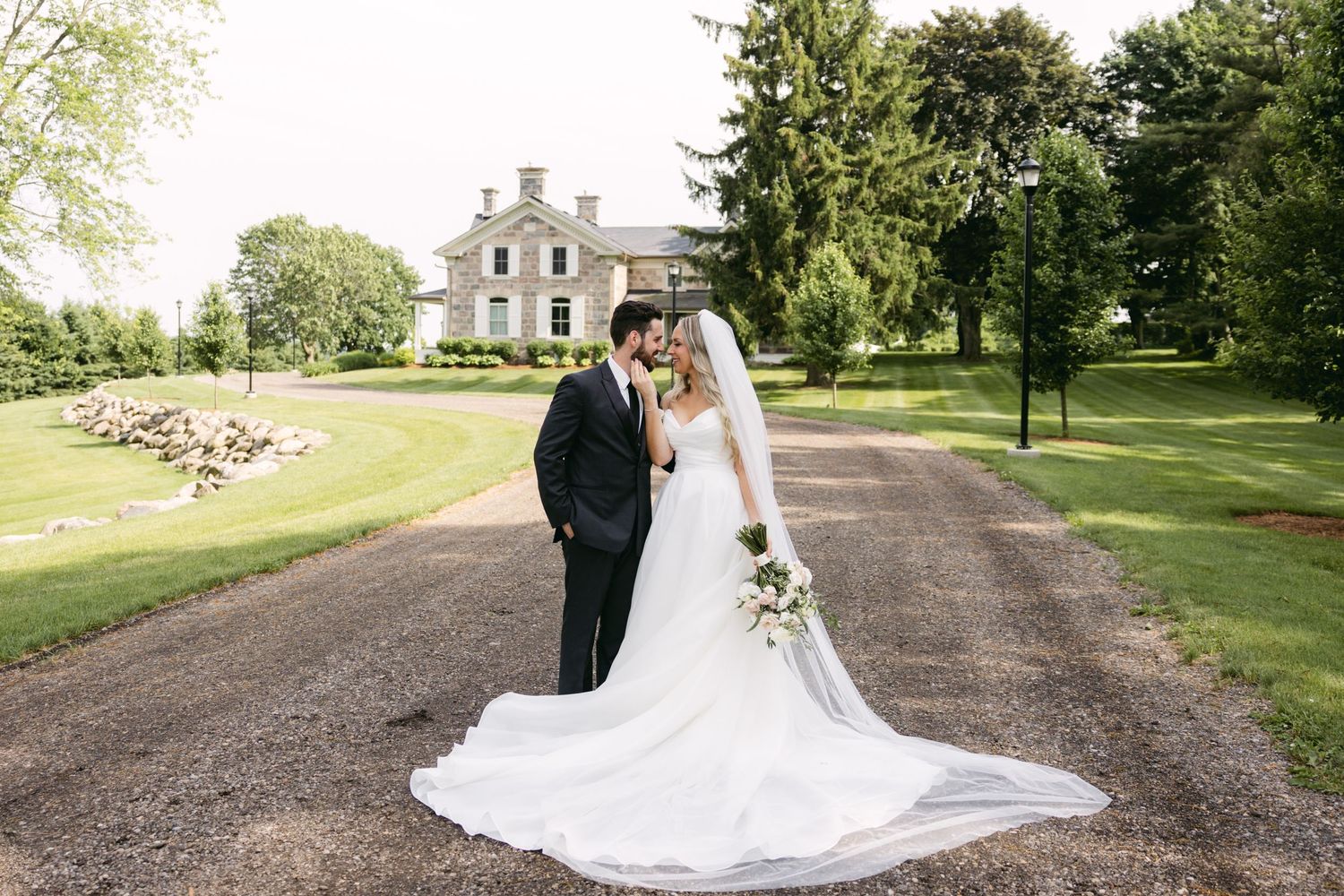 A classic wedding portrait featuring a historic mansion backdrop with manicured gardens and grounds.