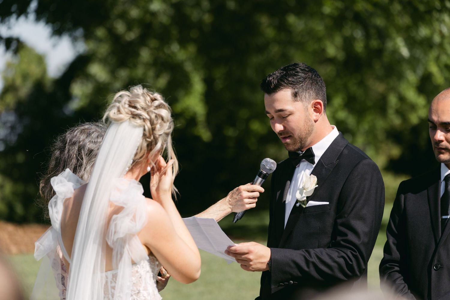 Couple sharing an emotional moment during their outdoor wedding ceremony on a sunny day.
