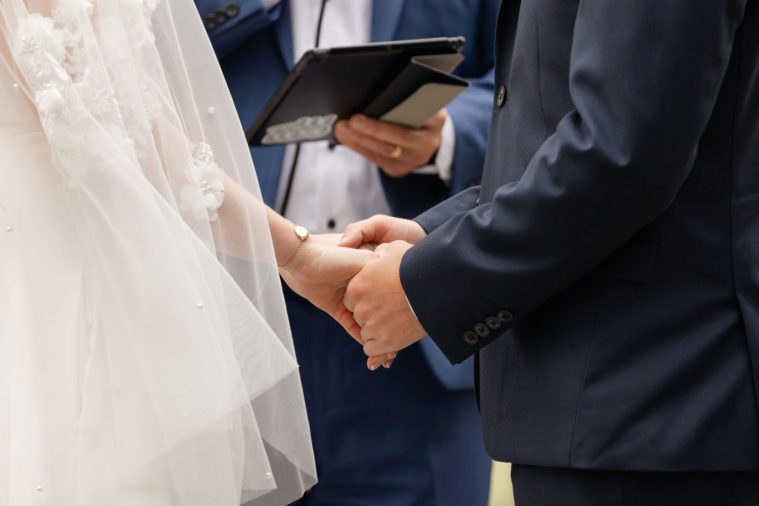 Close-up of hands during wedding ceremony exchange.