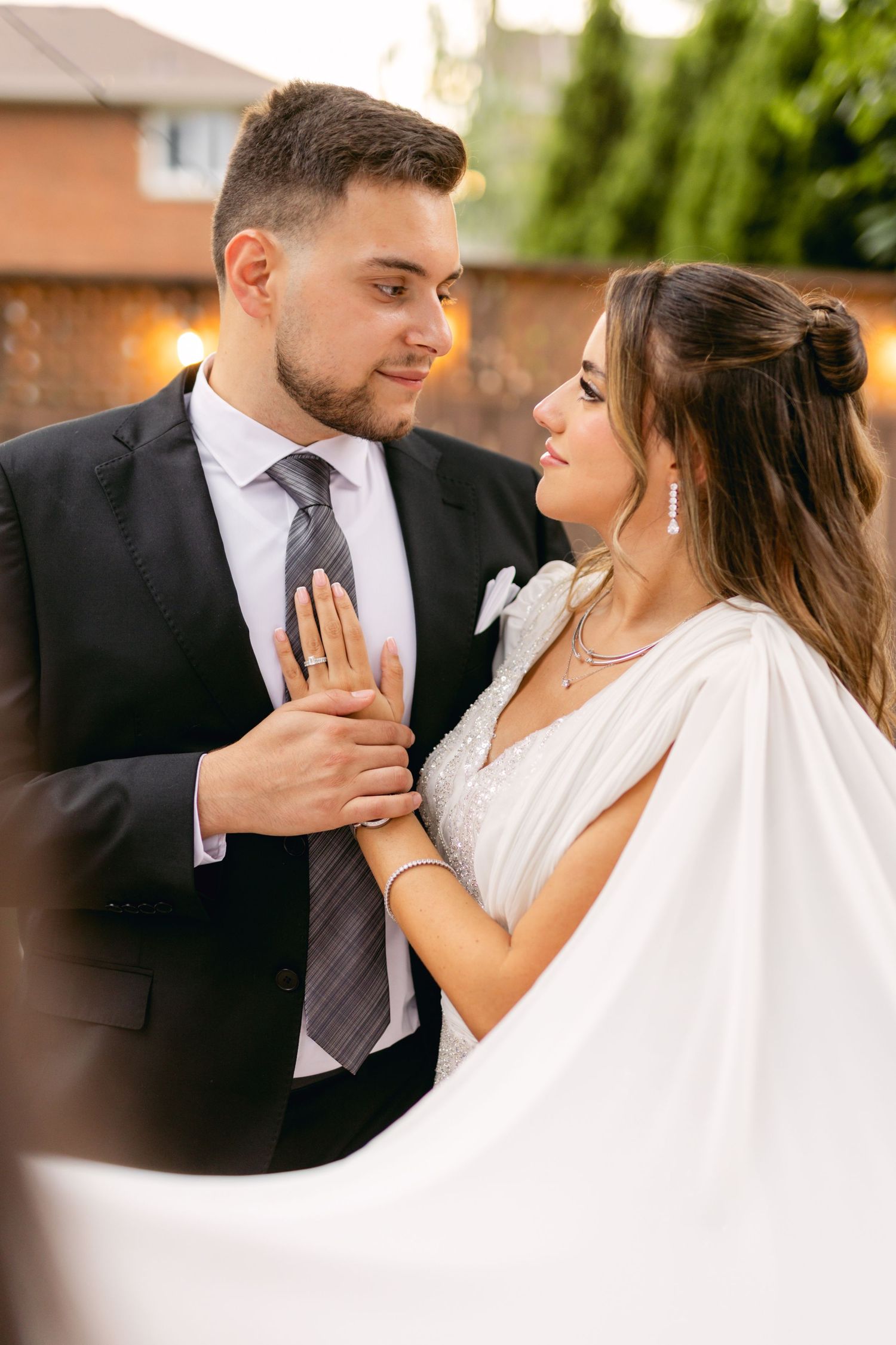 Intimate moment between newlyweds in formal attire outdoors.