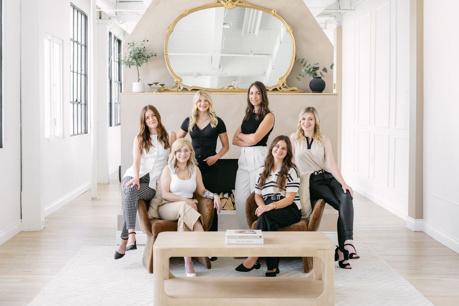 A group of people sitting in a bright white hallway with arched windows and modern minimalist decor.